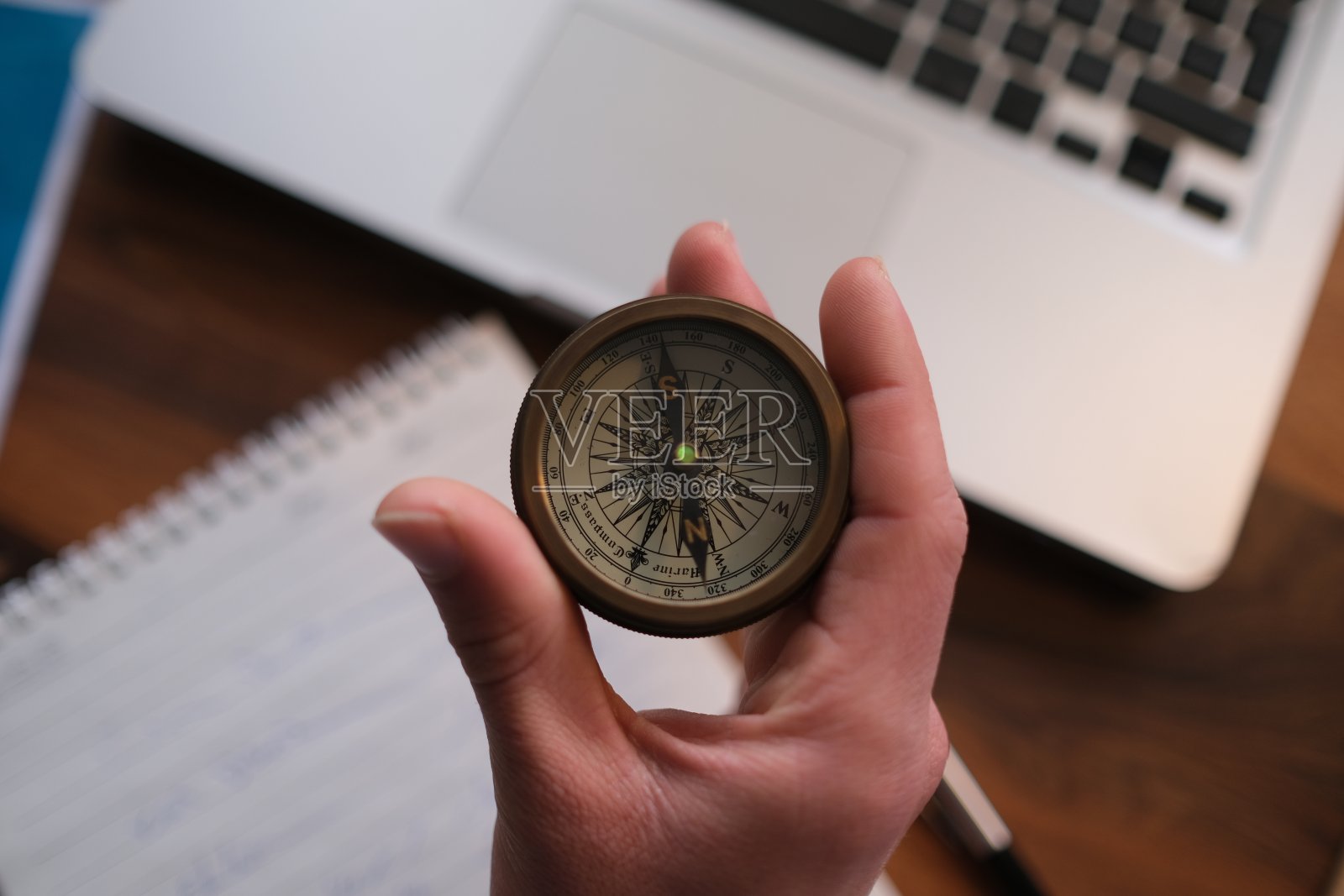 商人在笔记本电脑上拿着指南针，屏幕上显示客户网络连接图标，手机银行和全渠道照片摄影图片