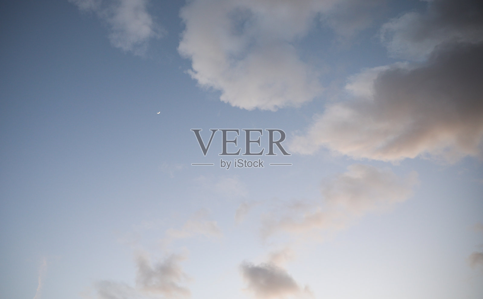 新月在傍晚的天空中被云柔和的光照在黎明照片摄影图片