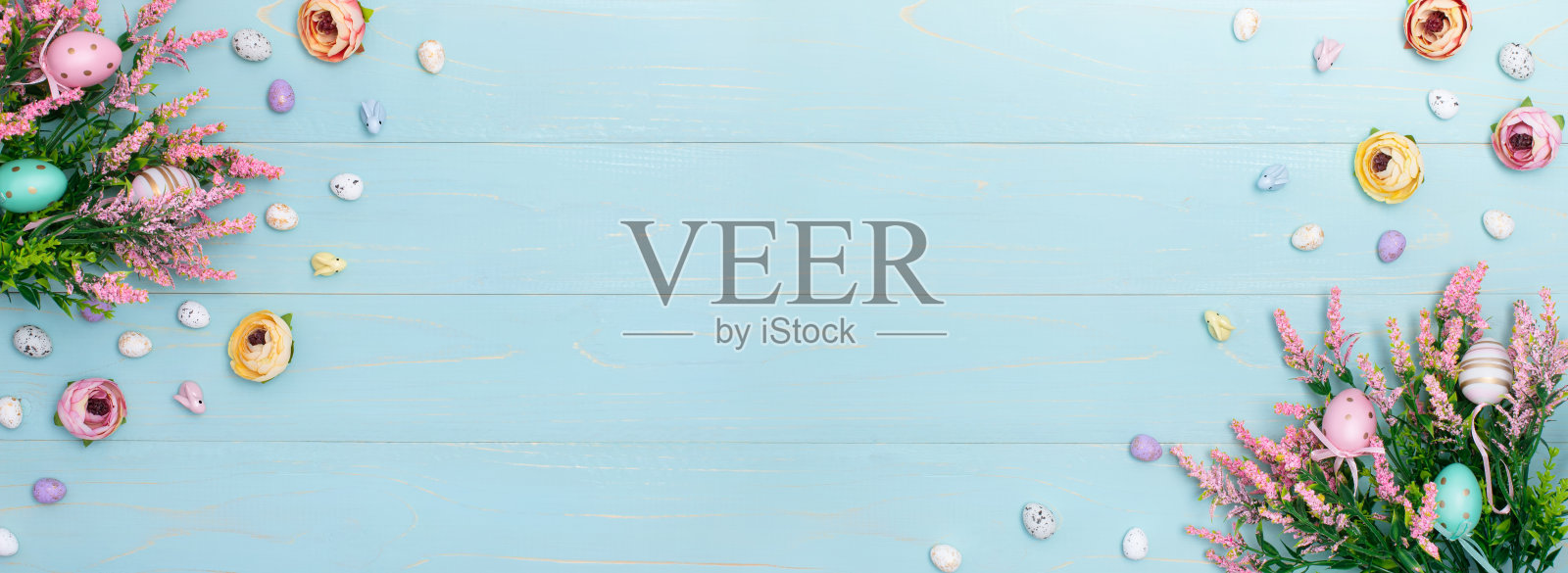 复活节的大横幅上有粉红色的春花，五颜六色的玫瑰，可爱的兔子和装饰性的鸡蛋。复活节广告内容，蓝色木制背景。平铺，俯视图，特写，复制空间照片摄影图片