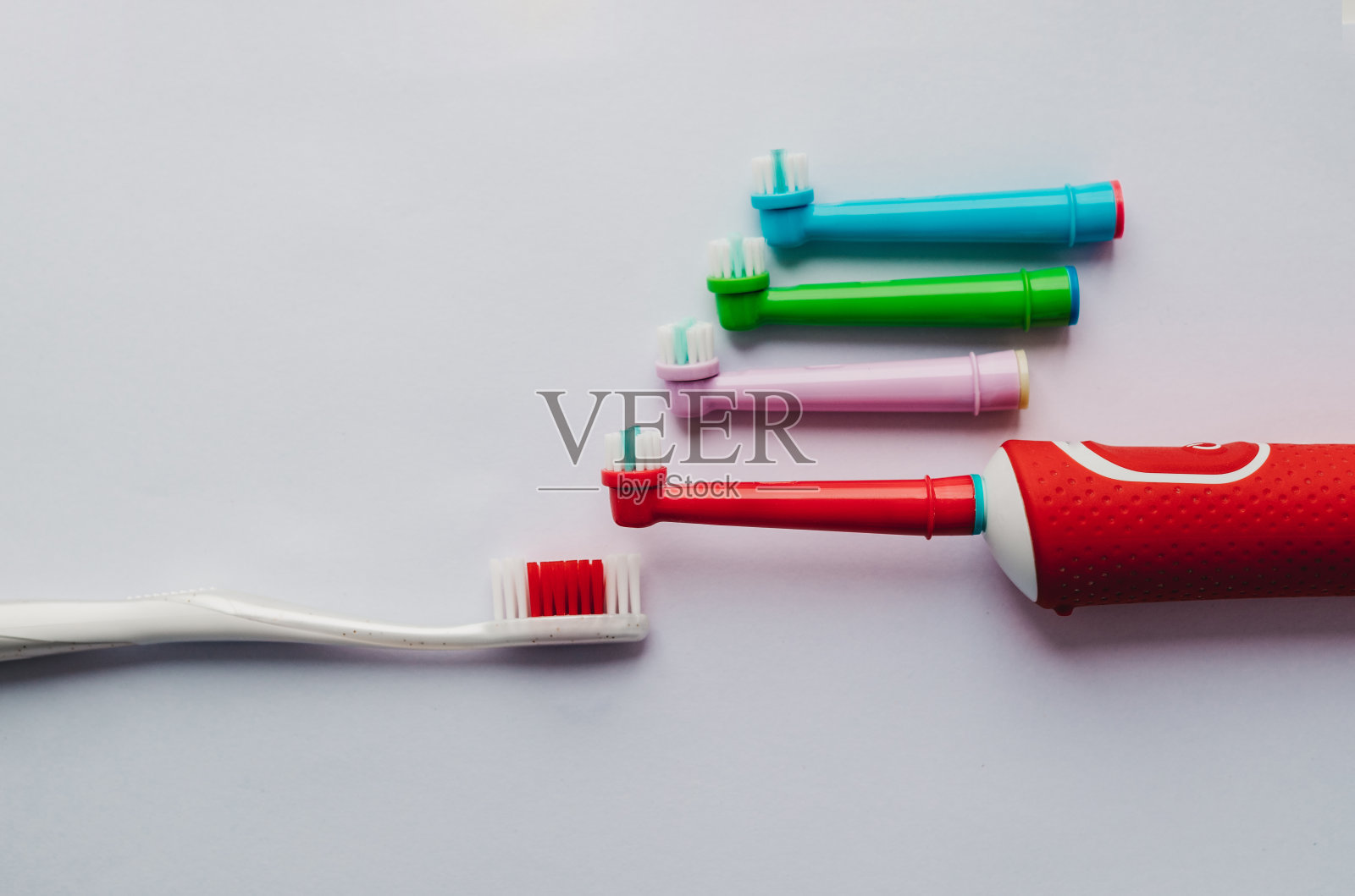 浴室充电器上的电动牙刷，有彩色附件照片摄影图片