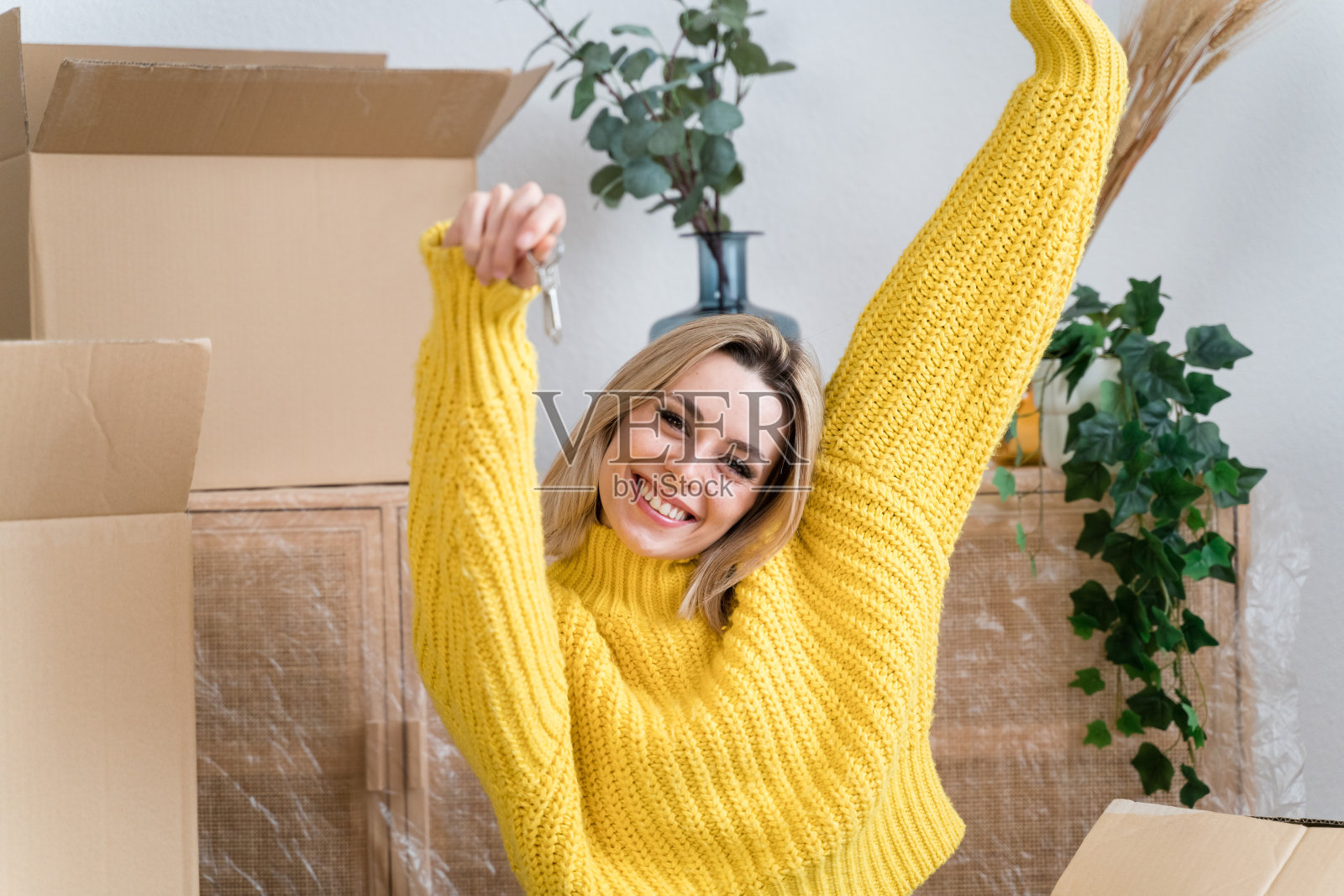 拿着新房子钥匙的纸箱的快乐女人照片摄影图片