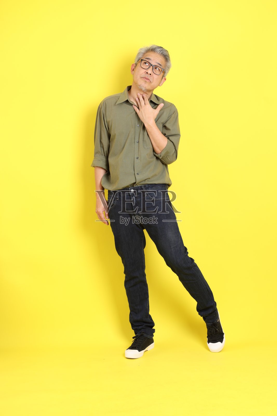 40多岁的亚洲成年男子，穿着休闲，站在黄色背景上。照片摄影图片