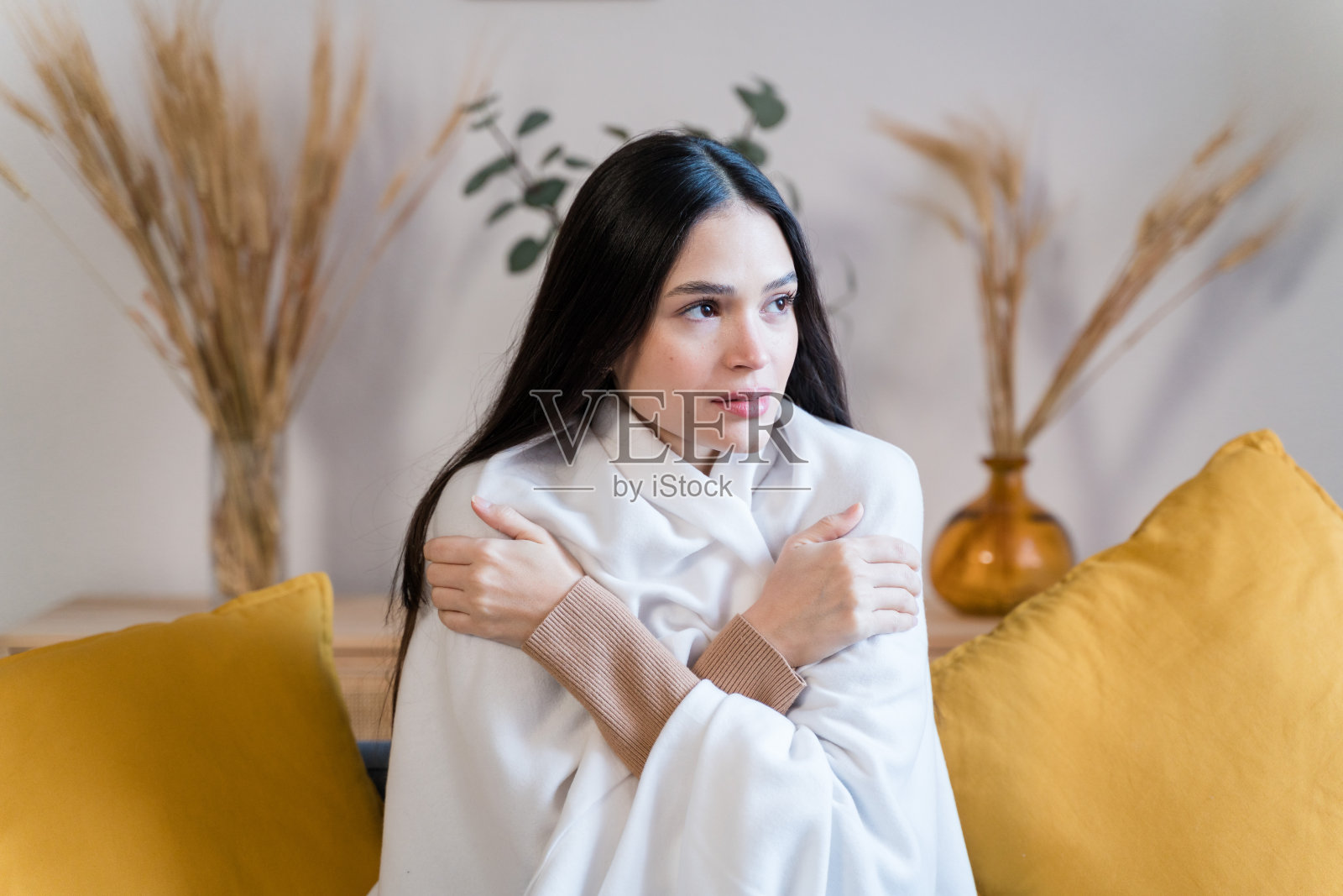 坐在沙发上的女人很冷，用毯子盖住自己照片摄影图片