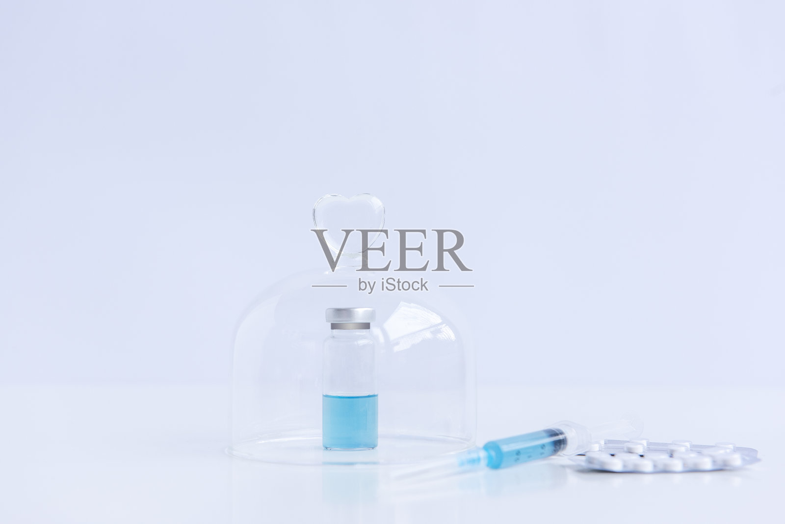 在孤立的白色背景上放着一个装有药物的注射器，一个装有蓝色病毒疫苗的小瓶照片摄影图片