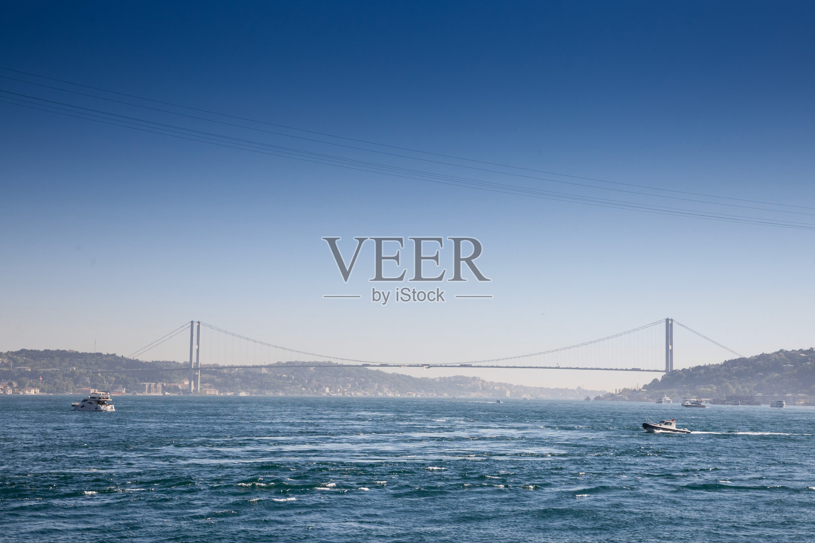 横跨博斯普鲁斯海峡的大桥;也被称为7月15日烈士桥或15 temmuz sehitler koprusu，从远处看，船只通过博斯普鲁斯海峡。它是伊斯坦布尔连接亚洲和欧洲的桥梁。照片摄影图片