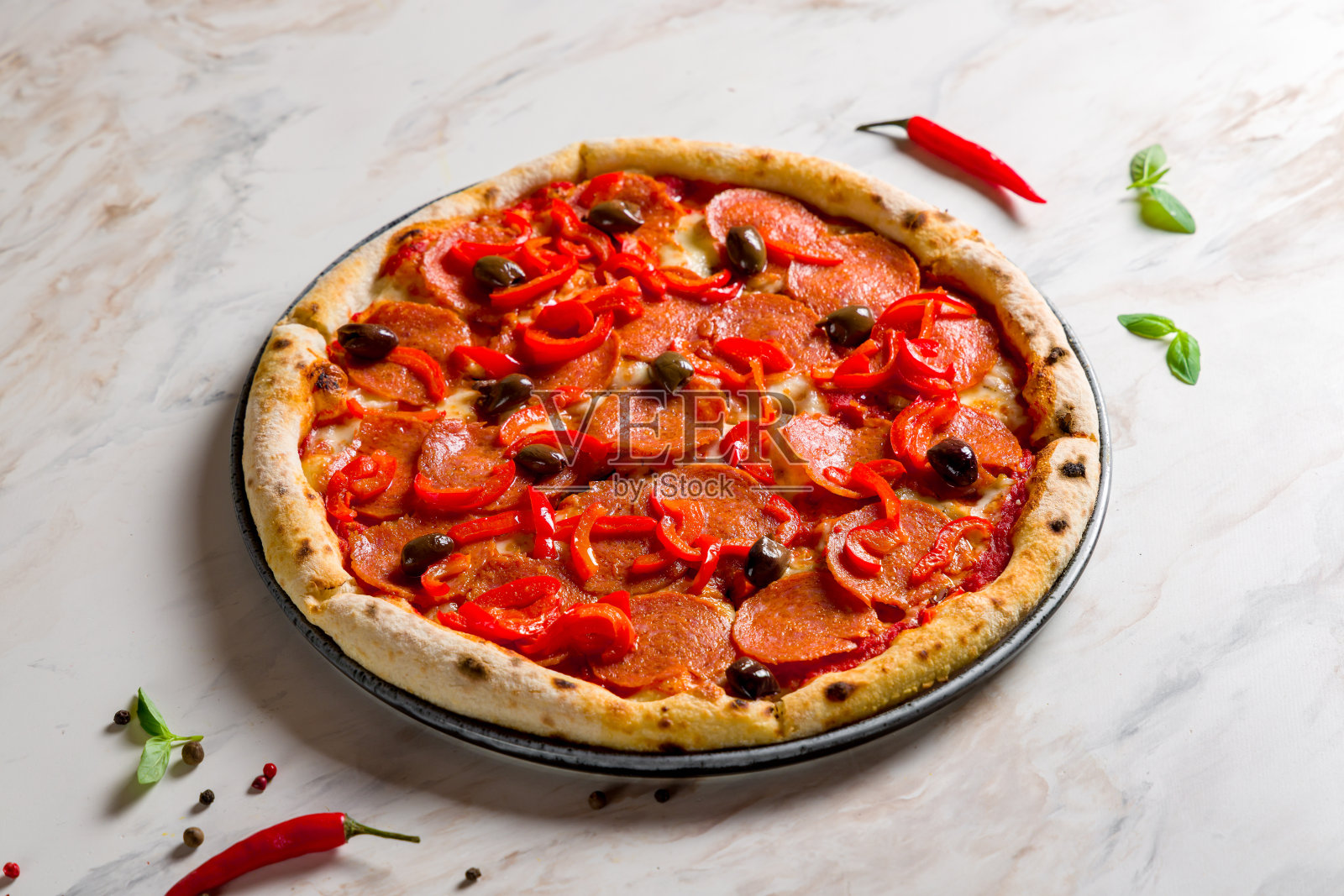 大理石桌上有橄榄和红辣椒的意大利辣香肠披萨照片摄影图片