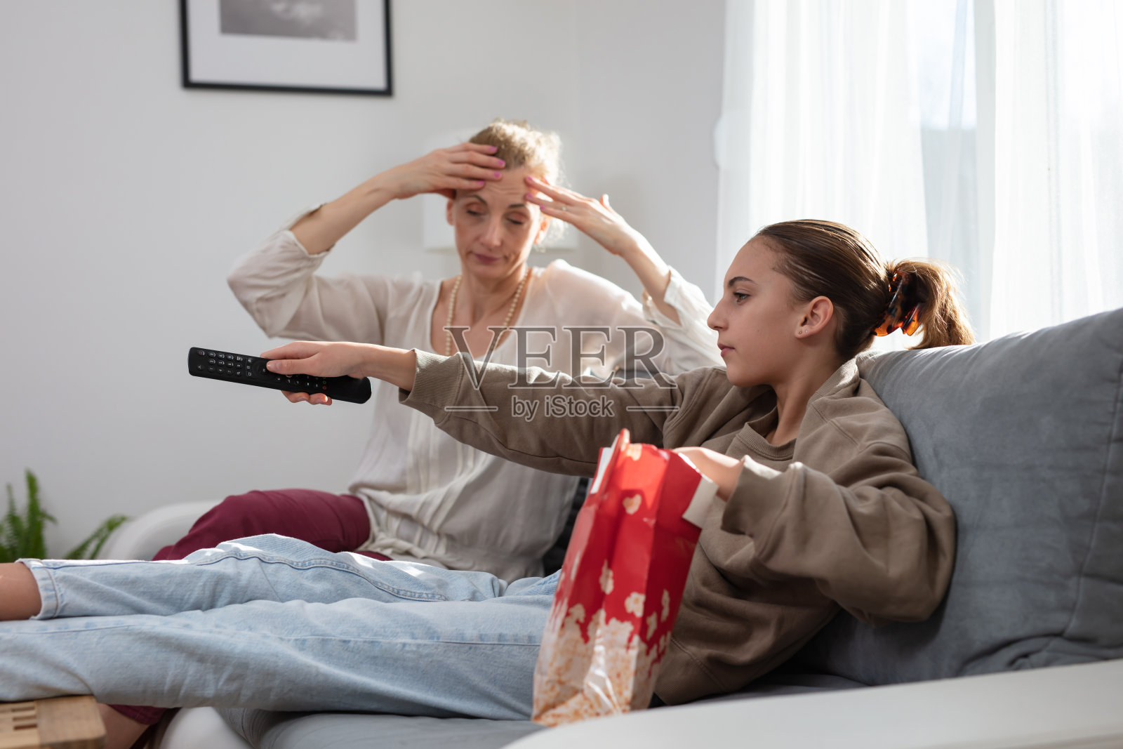 母亲在家看电视时与懒惰的青少年女儿发生争执照片摄影图片