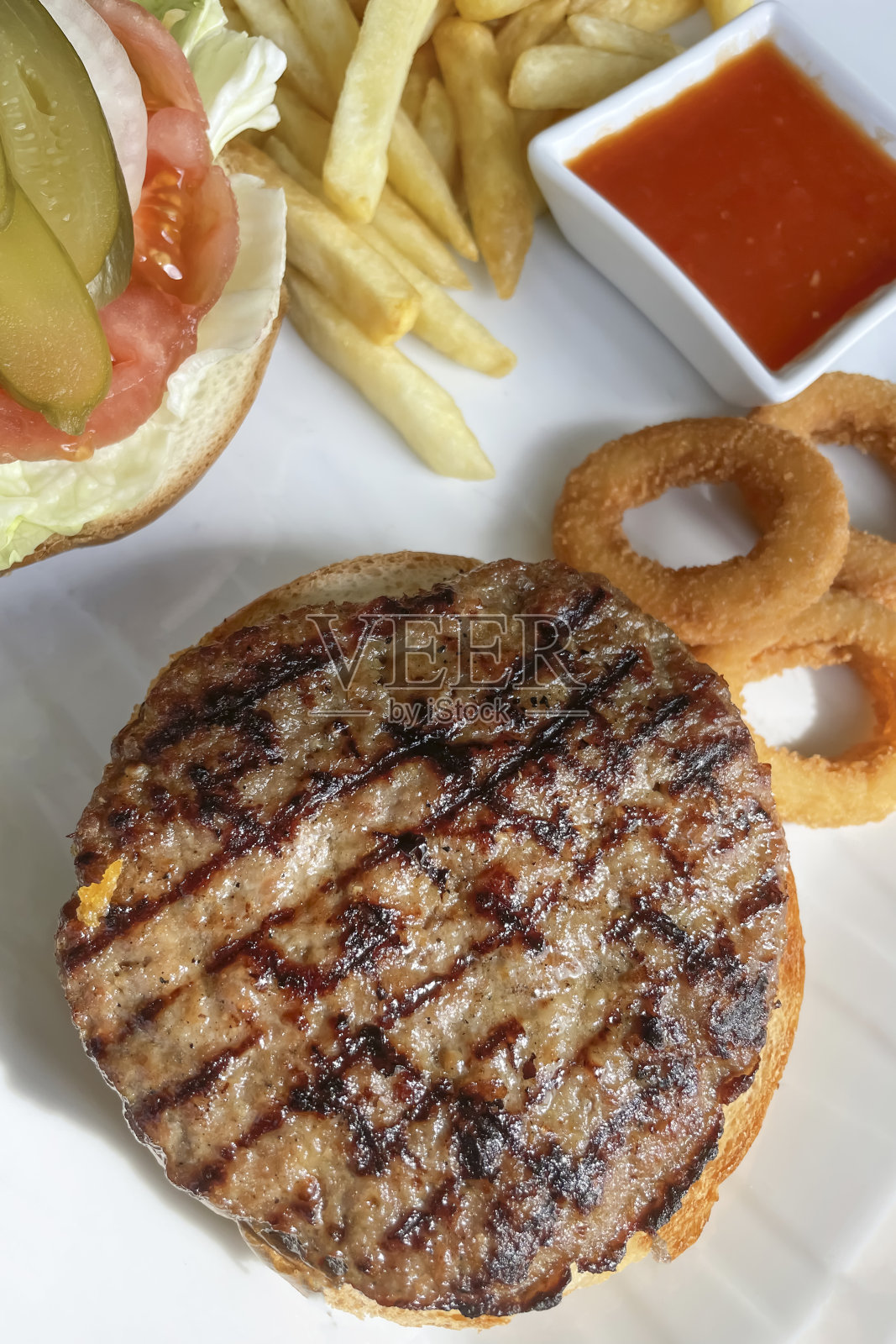 即食汉堡配炸薯条、洋葱圈和番茄酱。照片摄影图片