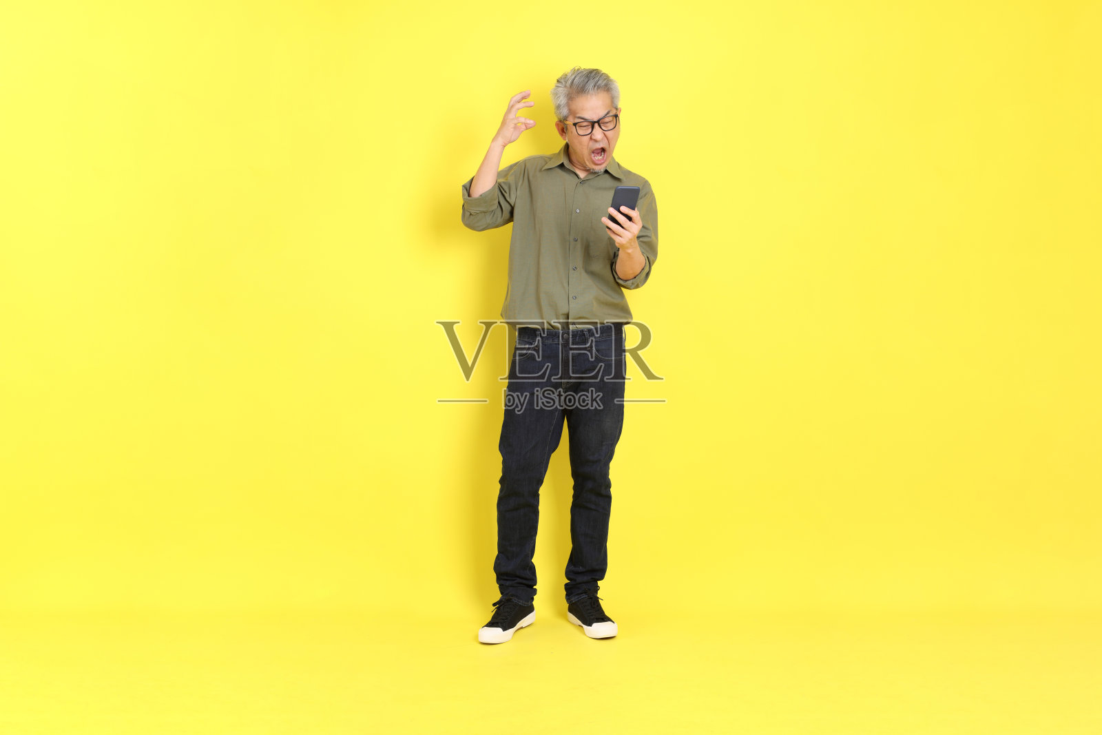 40多岁的亚洲成年男子，穿着休闲，站在黄色背景上。照片摄影图片