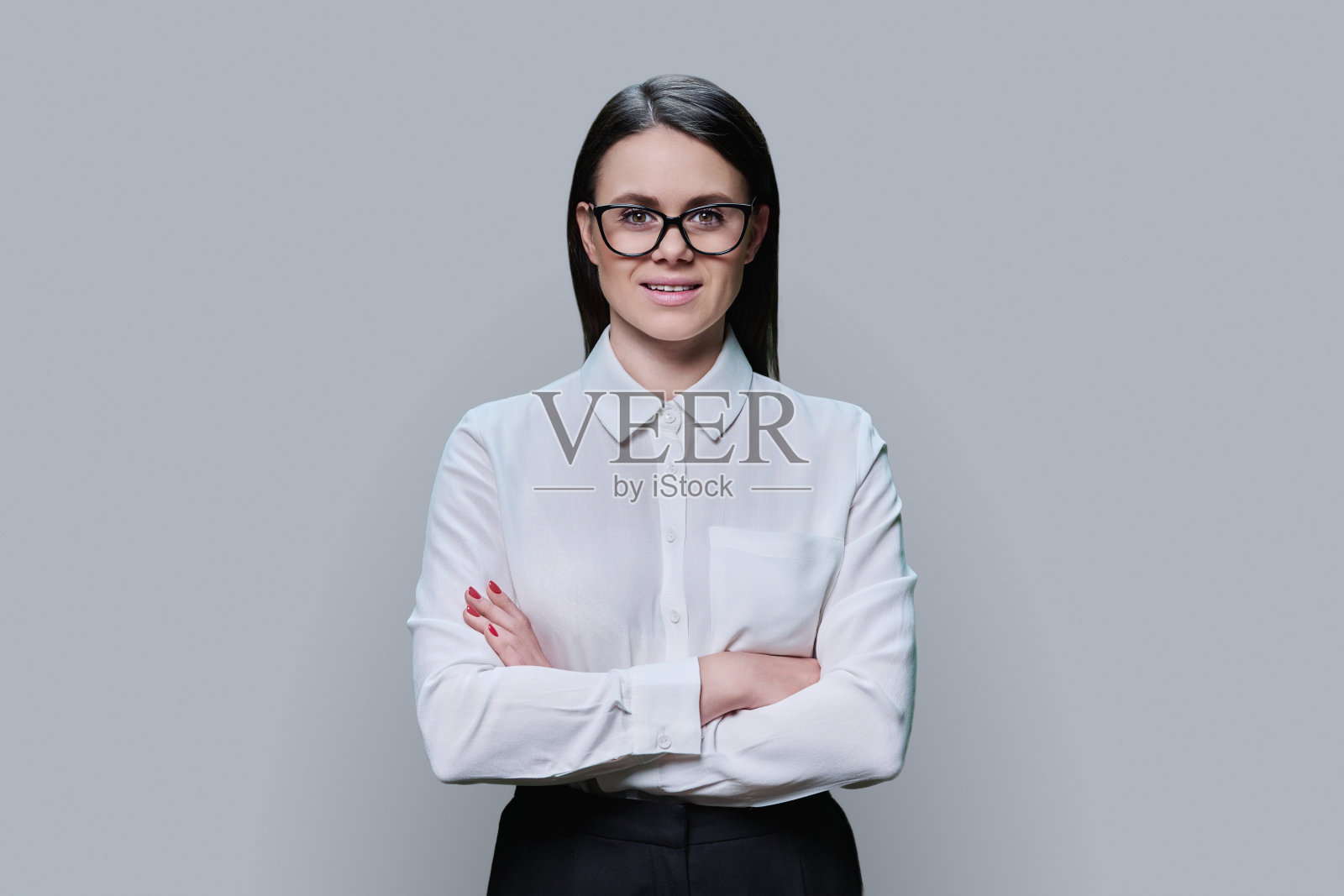 戴眼镜的年轻女子看着蓝色背景上的相机照片摄影图片