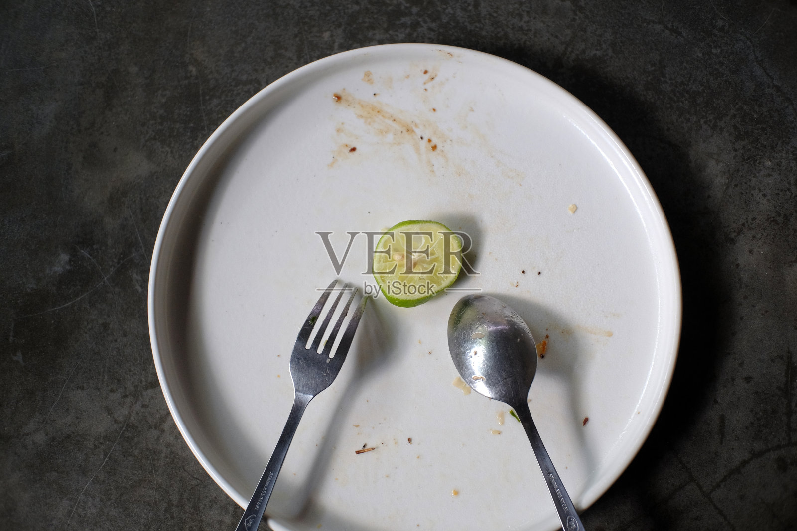 青柠片用刀叉放在白色盘子上，留下美味午餐的痕迹照片摄影图片