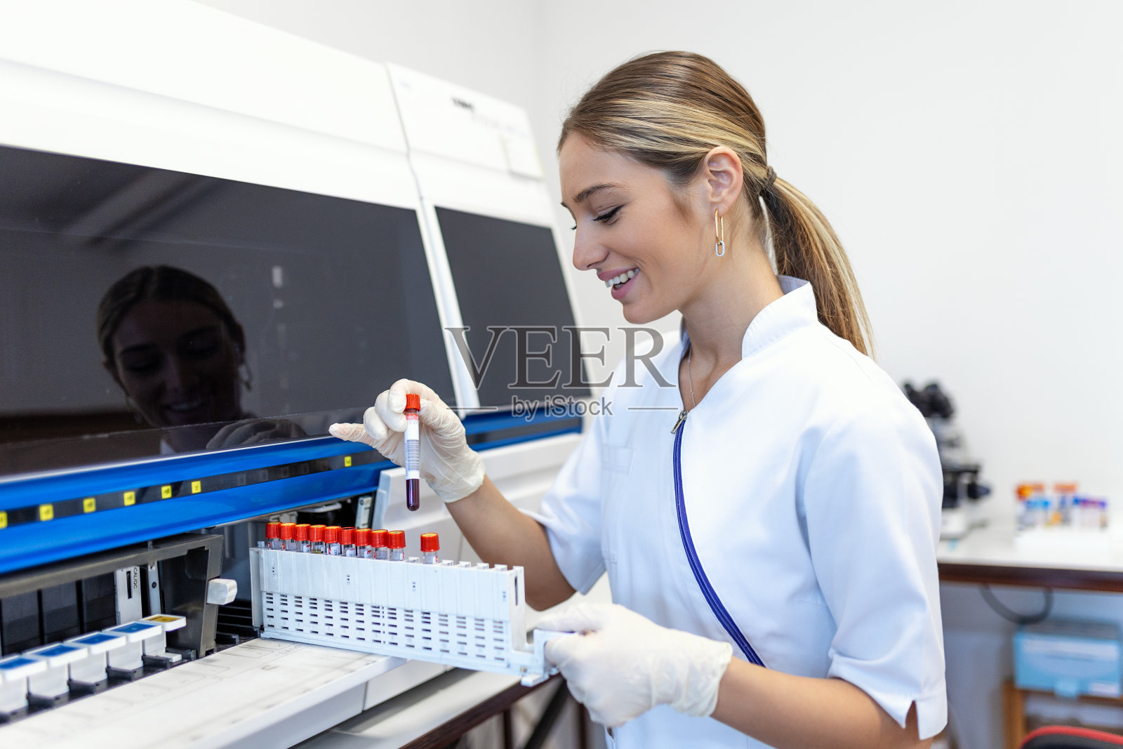 实验室技术人员正在把样品装进化学分析仪。女实验室技术员装载标本进行凝血试验分析照片摄影图片