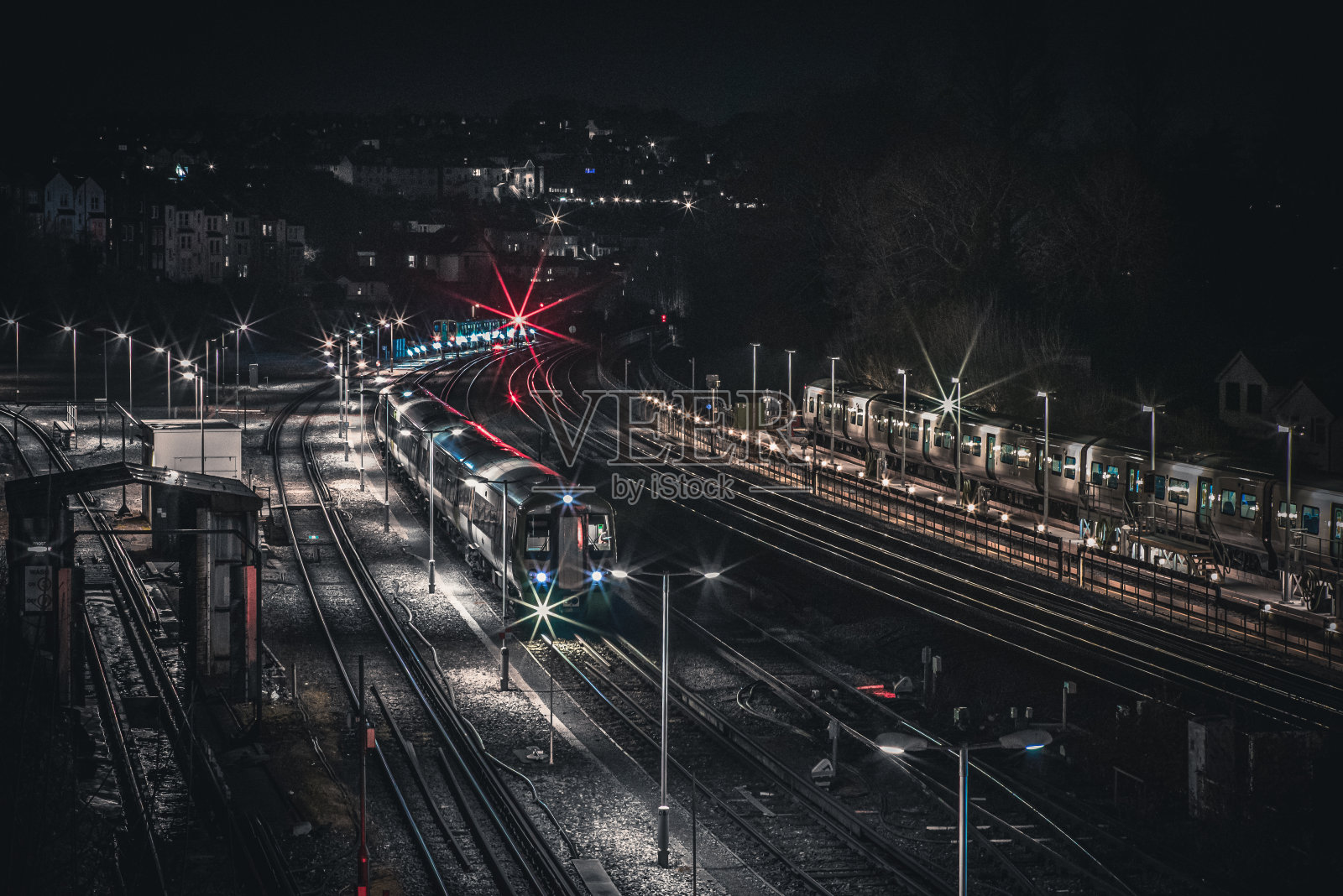 夜间站台旁的火车轨道随着火车驶来照片摄影图片