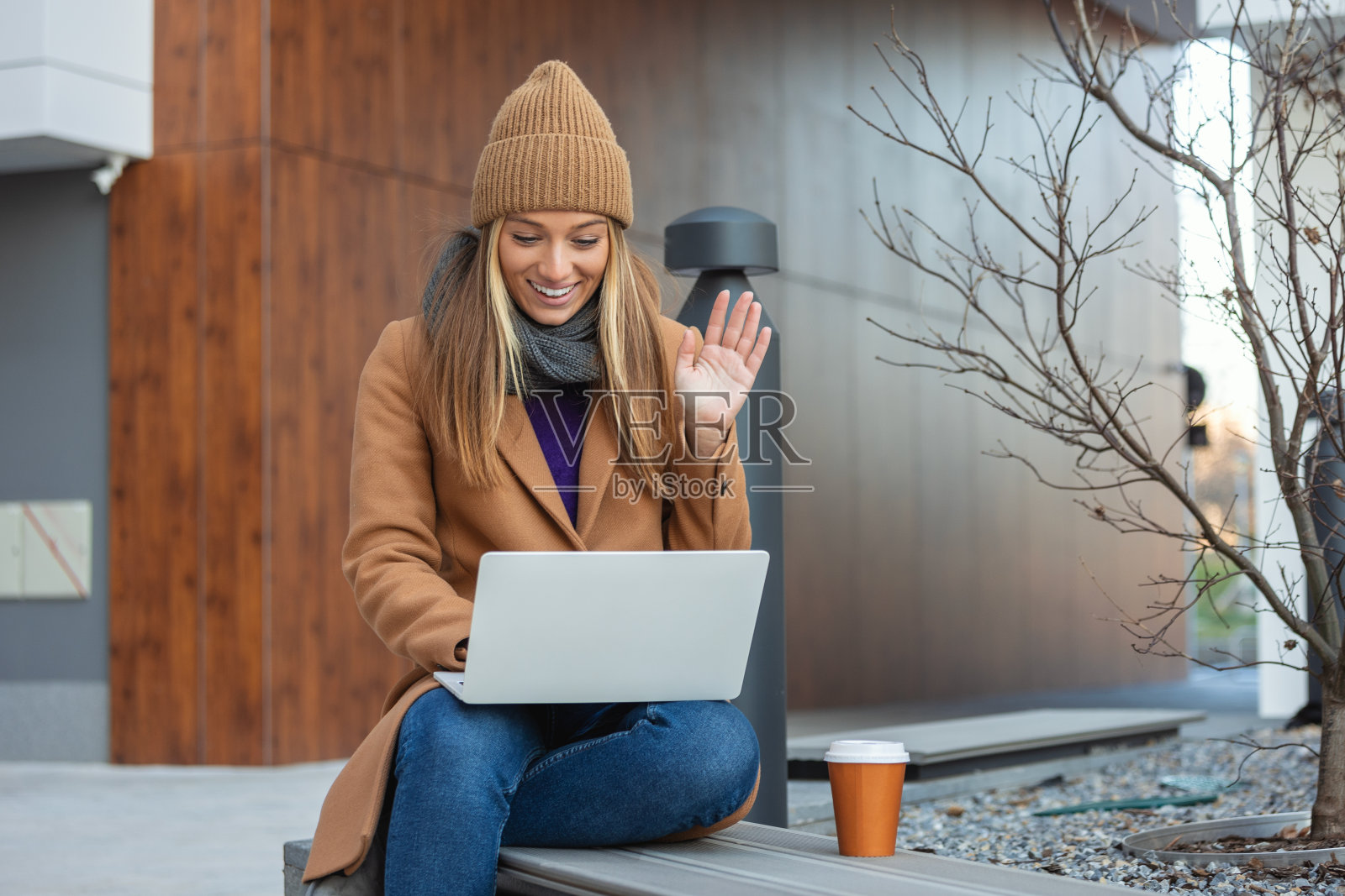 侧面的年轻女子在笔记本电脑上聊天，坐在长凳上，年轻的女性自由职业者在社交媒体上聊天照片摄影图片