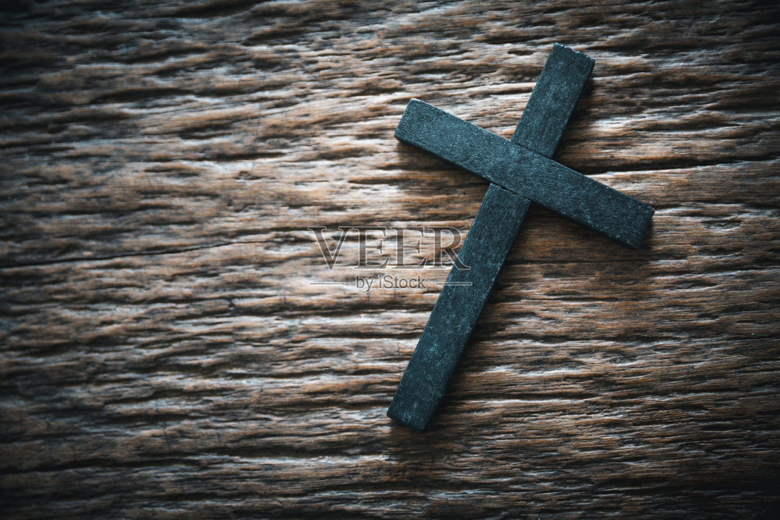一个木制的基督教十字架在垃圾板的背景。灰色桌子上的木制基督十字架，灯光模糊，文字空间。照片摄影图片