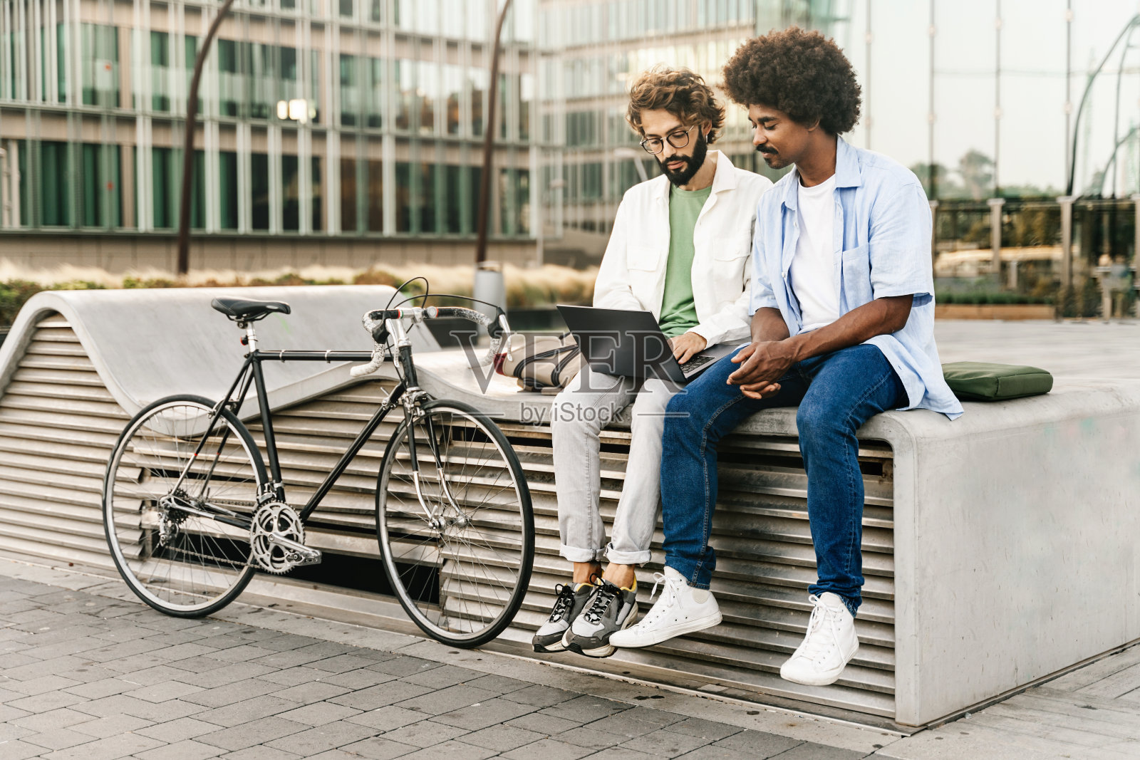 年轻的商业同事一起坐在户外自行车旁的笔记本电脑上工作照片摄影图片