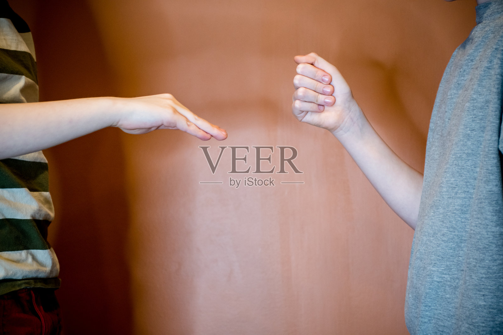 决定时间:男孩玩剪刀石头布，布打败石头照片摄影图片