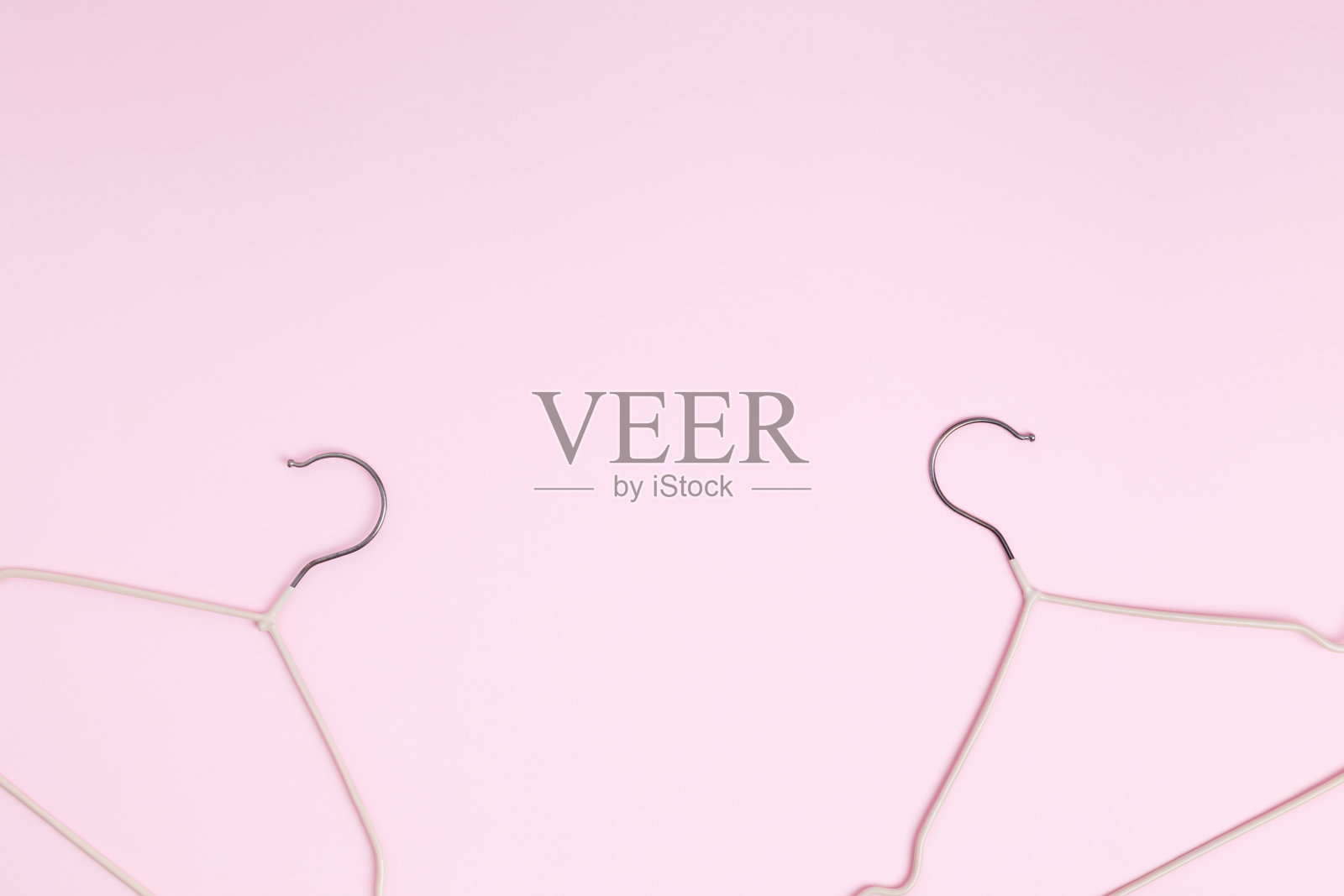 创意平铺衣架粉彩粉红色背景。销售折扣店促销购物概念。前视图。本空间照片摄影图片