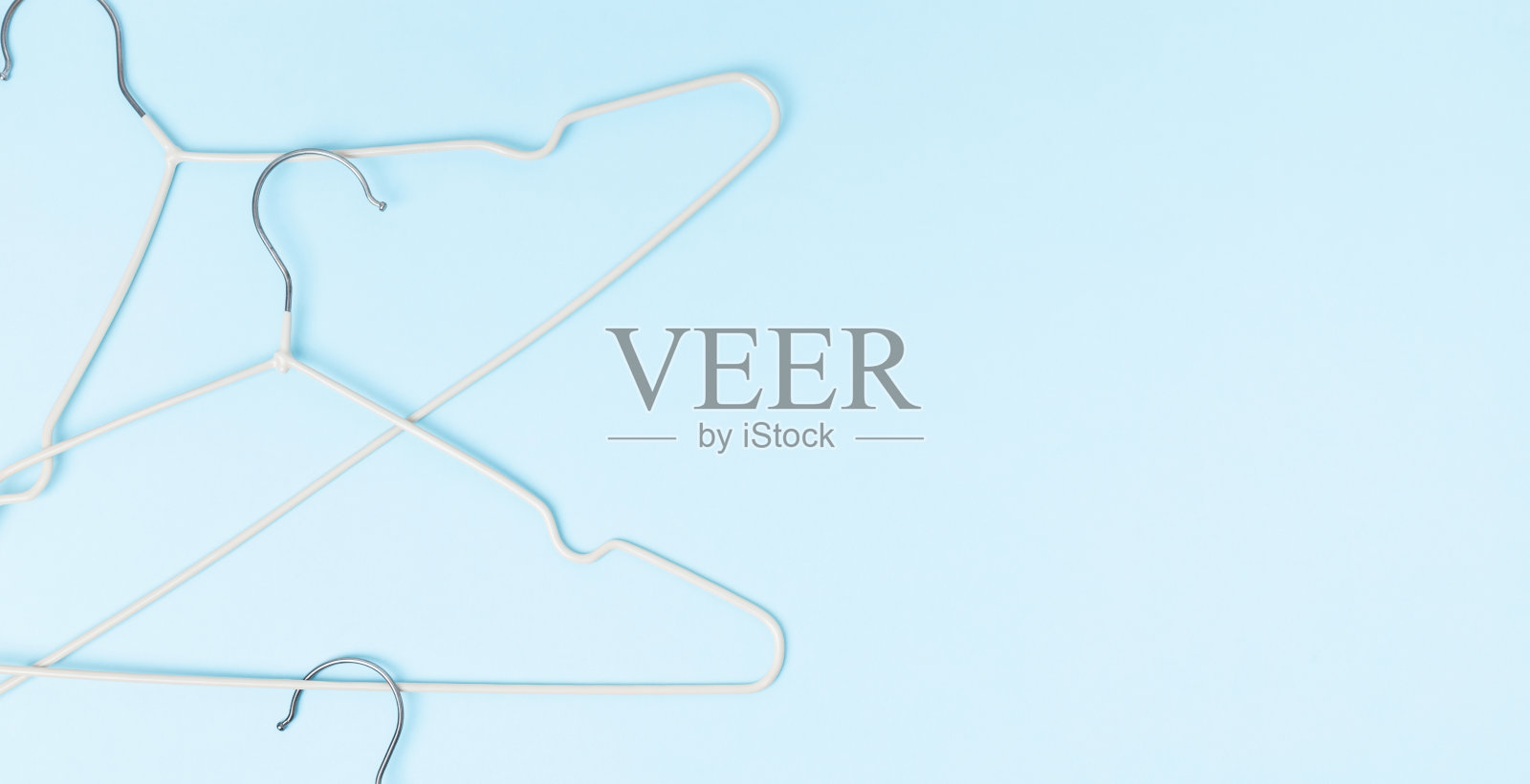 创意平铺衣架粉彩蓝色背景。销售折扣店促销购物概念。前视图。本空间照片摄影图片