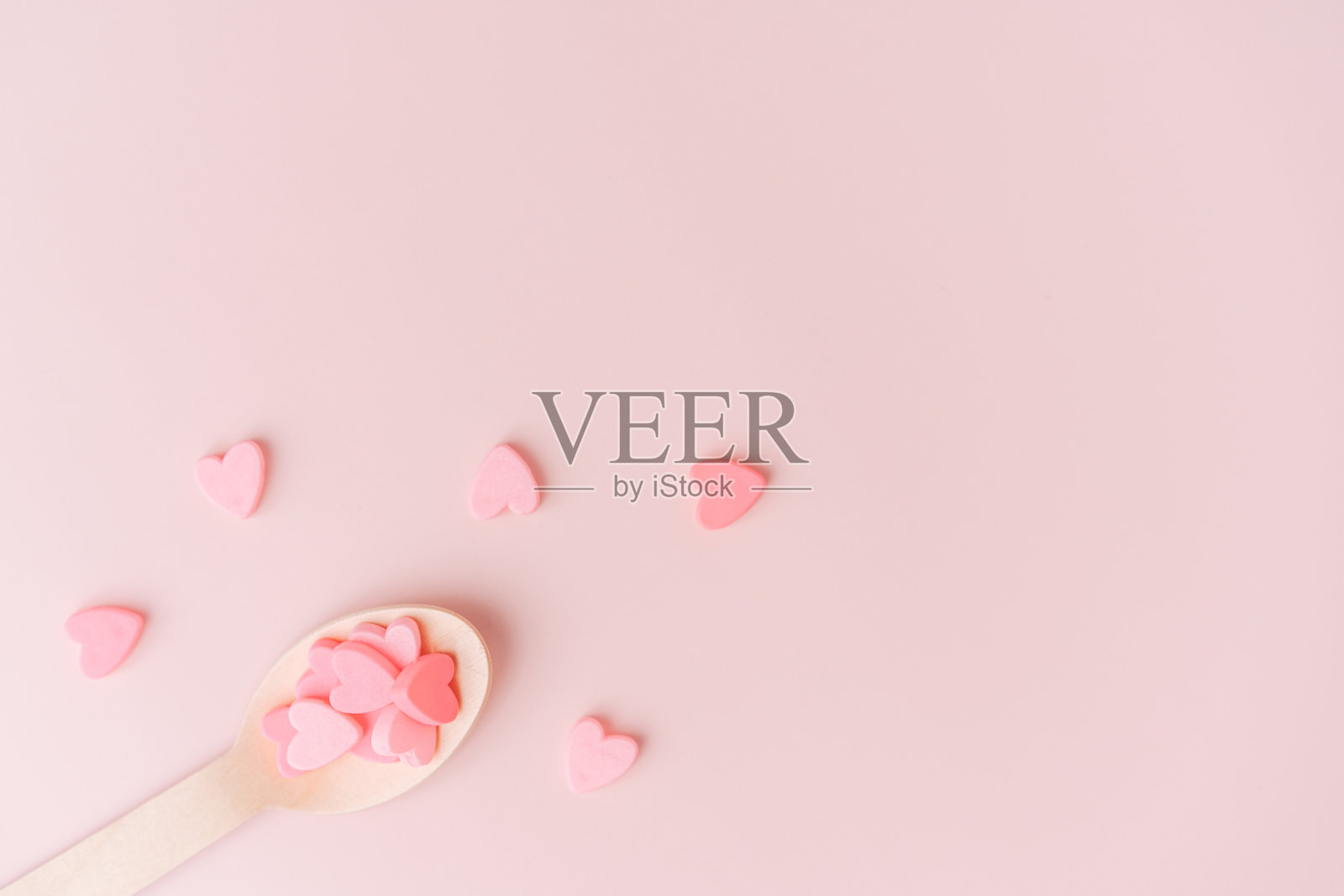 粉色背景上有粉色心形的木勺照片摄影图片