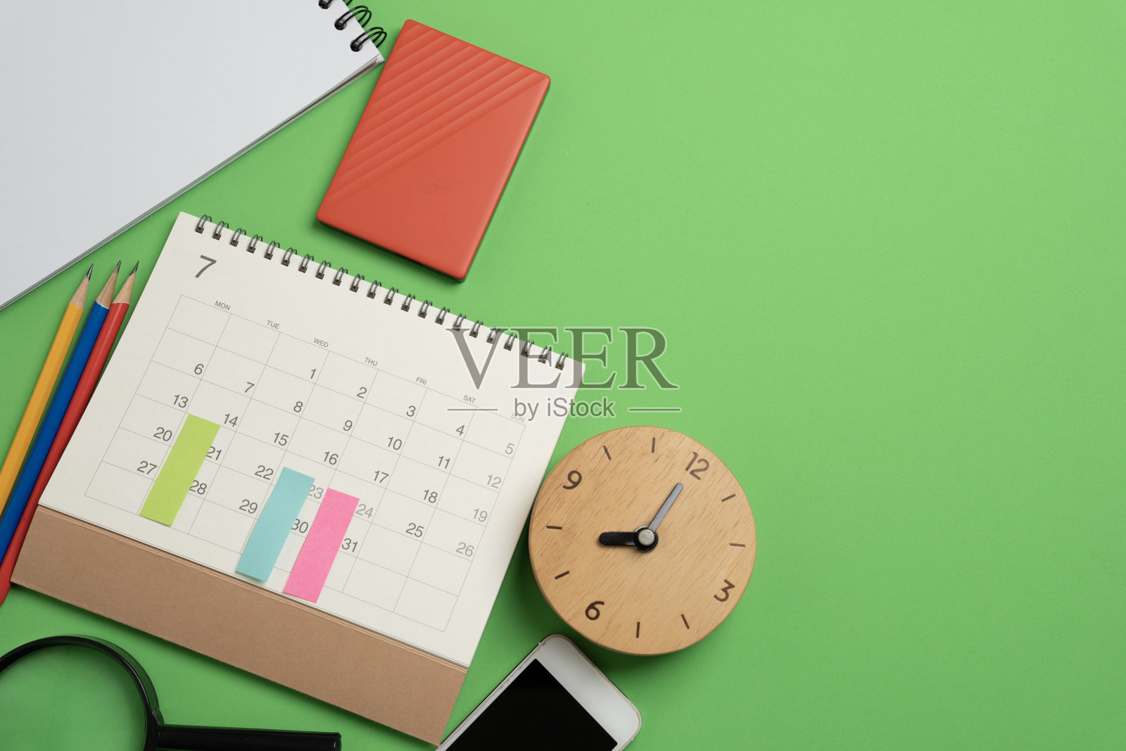 近距离的日历和时钟在绿色桌子背景在办公室，计划商务会议或旅行计划的概念照片摄影图片