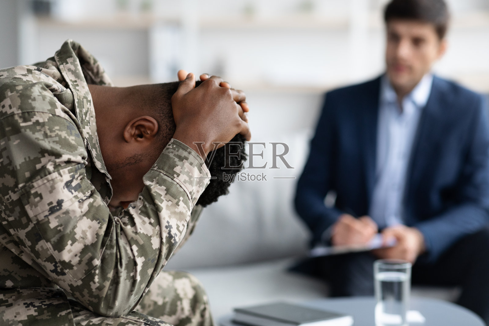 在诊所拜访心理治疗师的沮丧黑人士兵照片摄影图片
