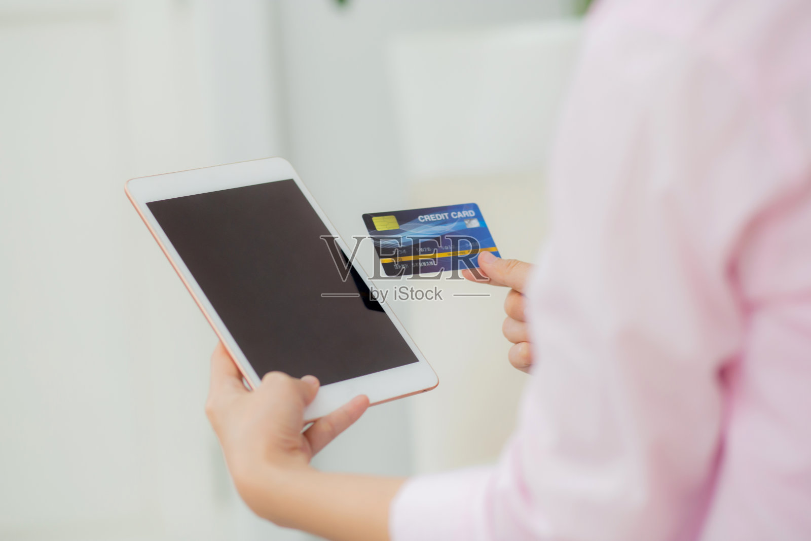 年轻的亚洲女性手持信用卡在网上购物，用平板电脑空白显示屏购买和支付，女性使用借记卡购买或交易，商业和电子商务概念。照片摄影图片