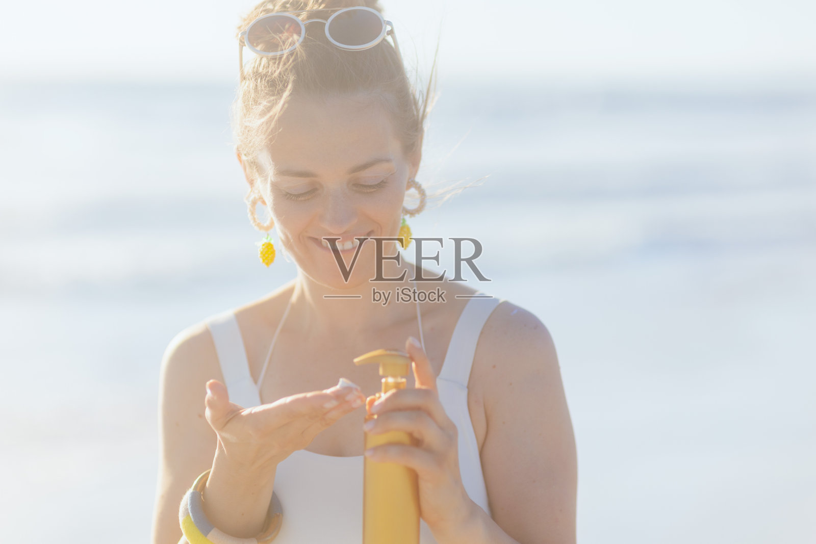 微笑的现代女子在白色泳衣与SPF在海滩照片摄影图片