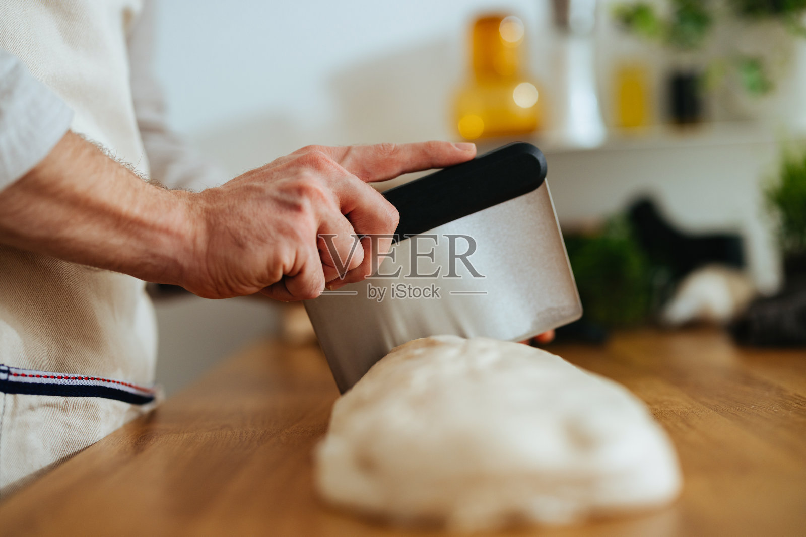 特写镜头是一个不知名的男人在厨房里切面团照片摄影图片