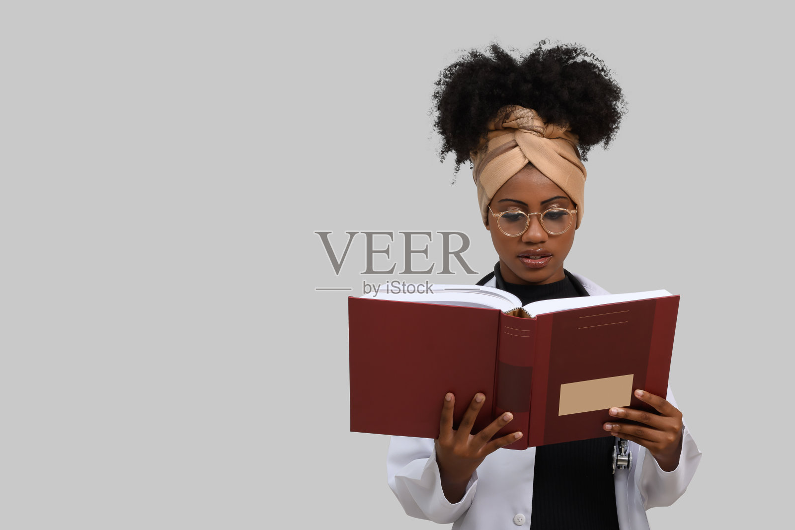 年轻女医学生带着教科书在灰色背景上照片摄影图片