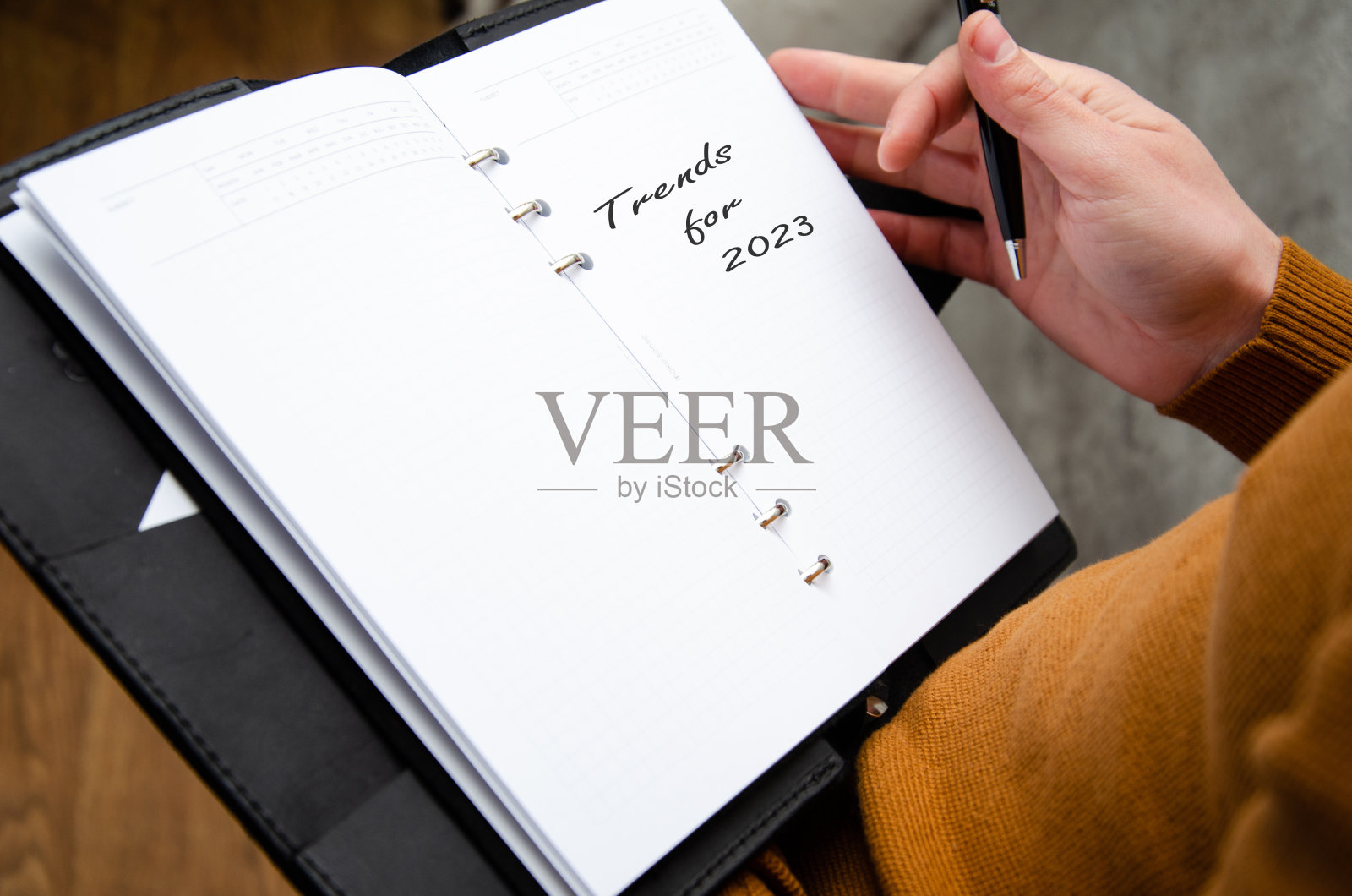 2023年的趋势，一个人在一个灰色的水泥纹理背景的笔记本上写着一个计划。的生活方式。照片摄影图片