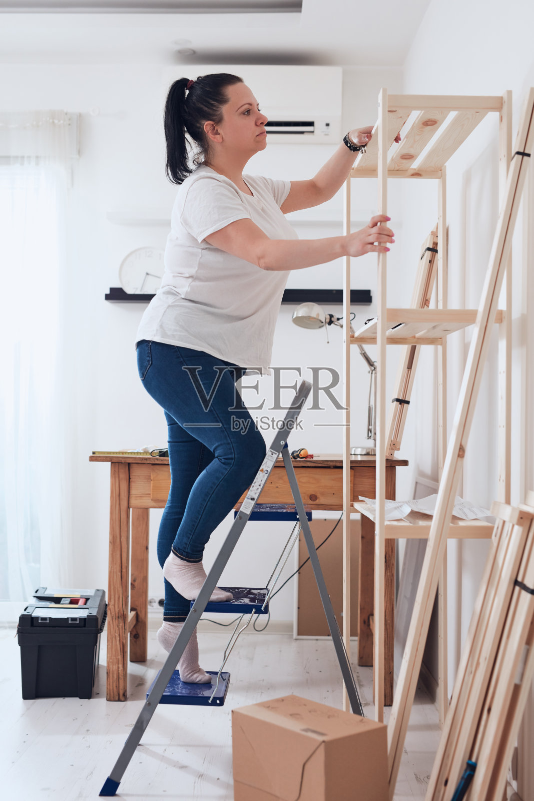 在公寓里组装新木架和家具的女人。照片摄影图片
