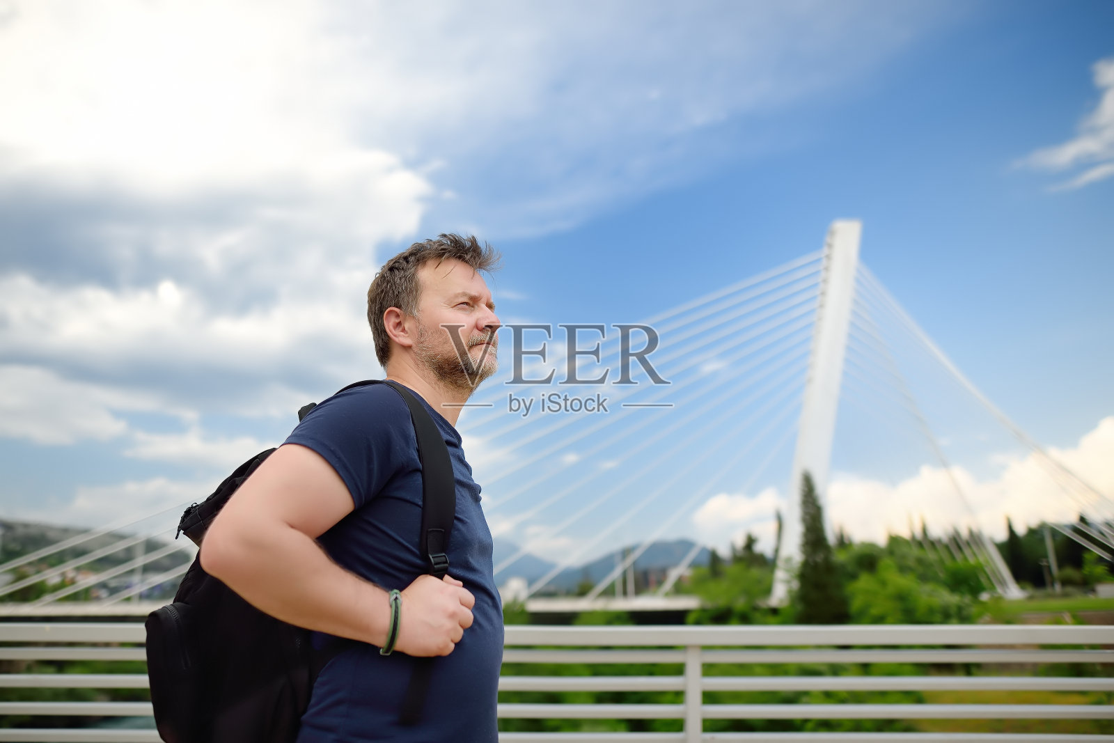 斜拉桥背景上的中年男子肖像。千年桥位于黑山波德戈里察的莫拉卡河上。照片摄影图片