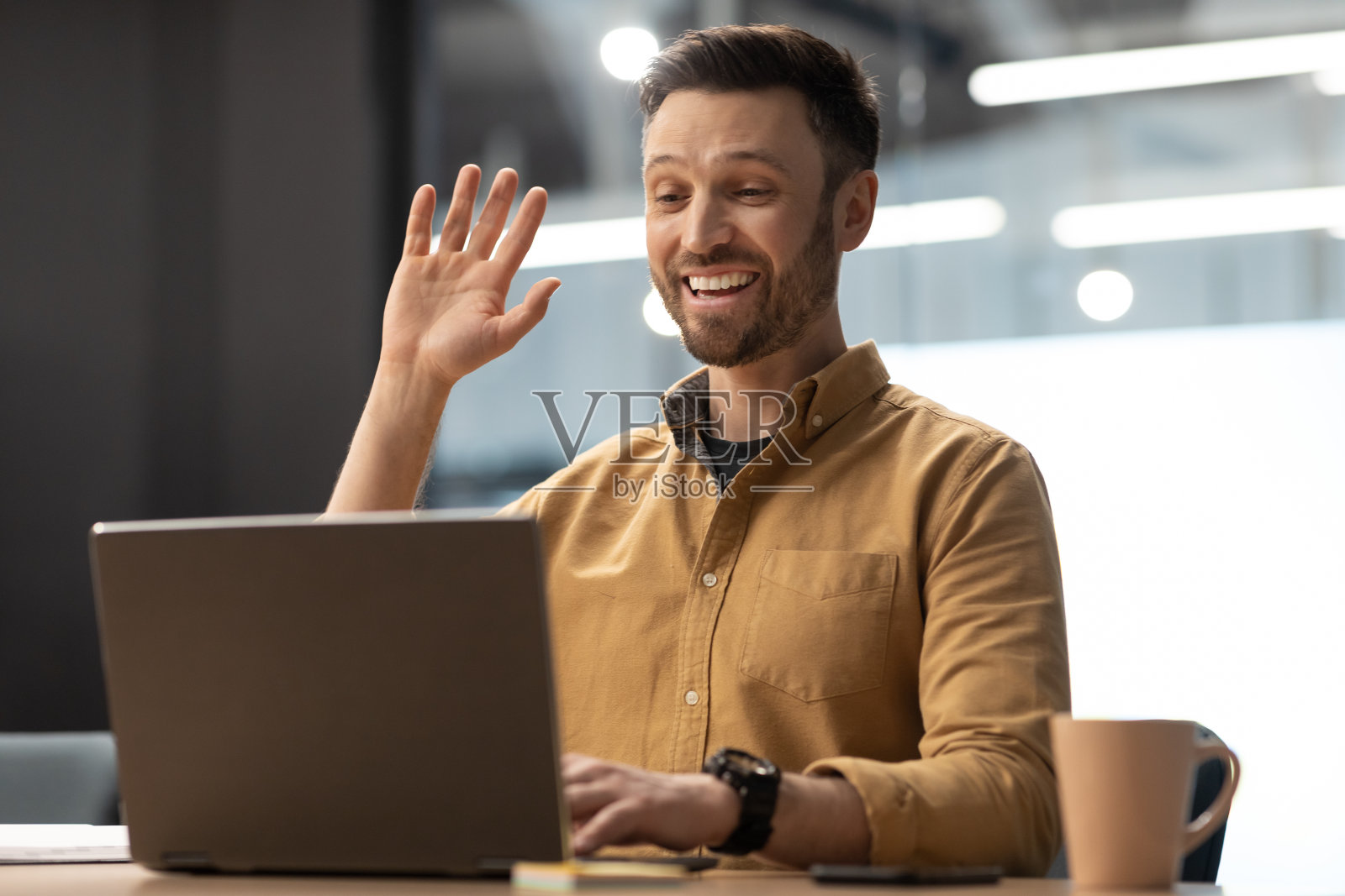 兴奋的商人挥手向笔记本电脑视频电话在办公室照片摄影图片