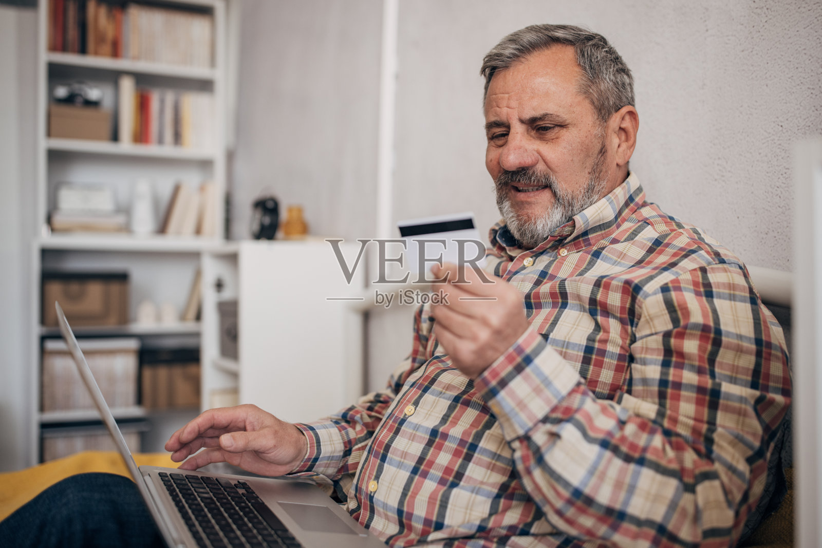 一位留着胡子的老人正在家里用笔记本电脑网购照片摄影图片