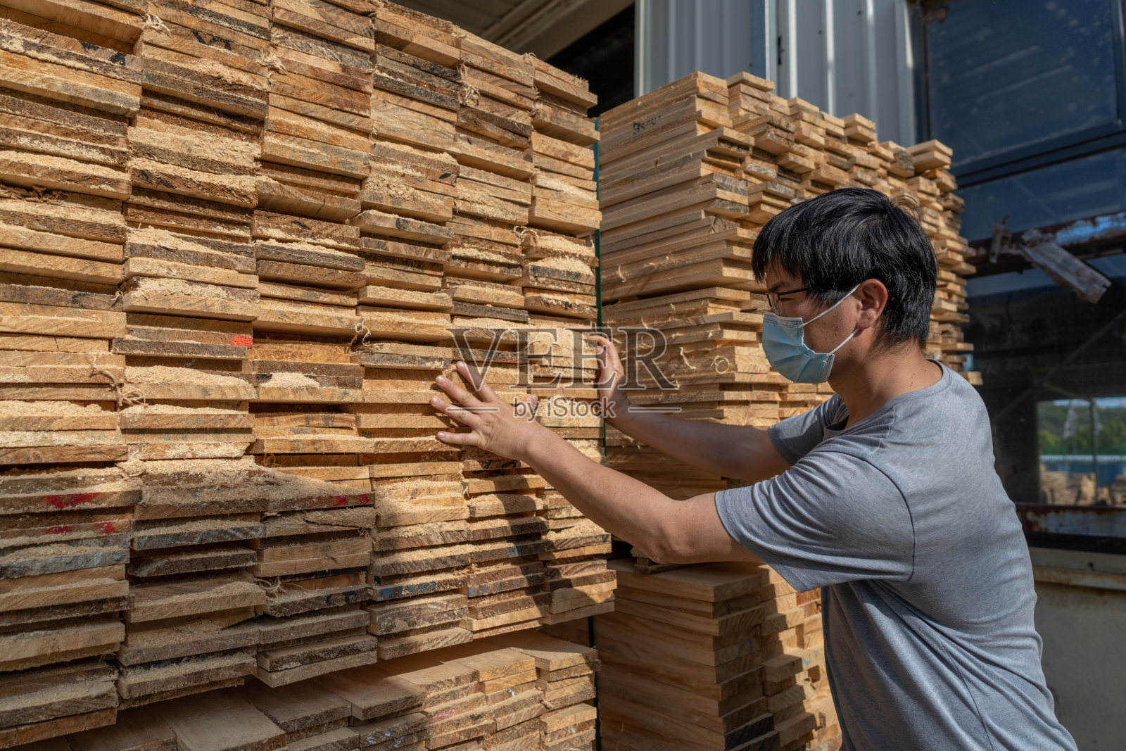 一名戴着口罩的男性工人正在检查木材照片摄影图片