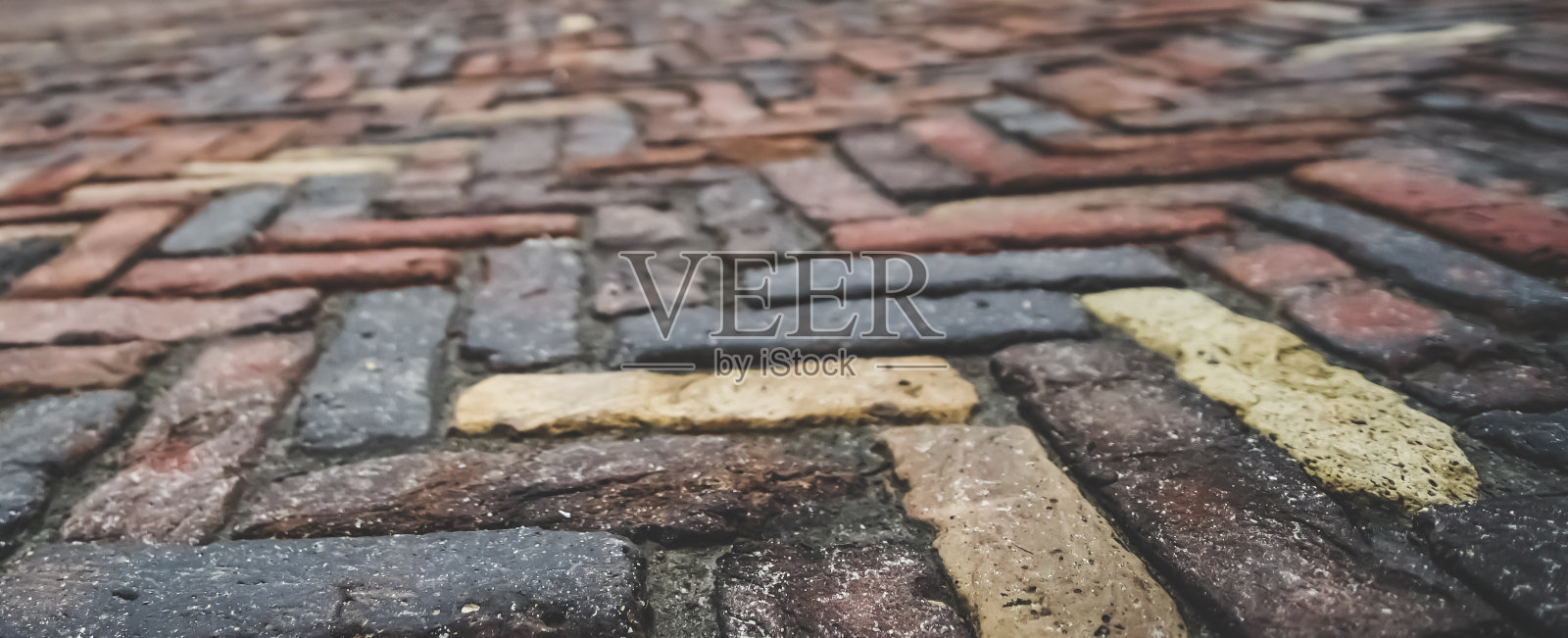 在一个阴云密布的雨后春日，切尔尼赫夫市，不同深浅的古董铺路石被铺成人字形，就像镶木地板一样，背景模糊照片摄影图片