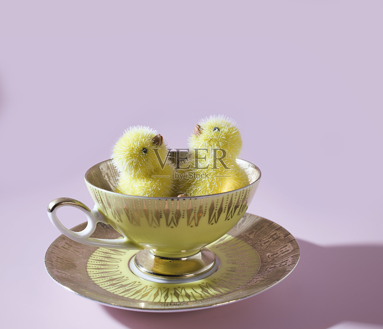 春天茶点的珍宝:可爱的小鸭子在淡黄色的杯子里照片摄影图片