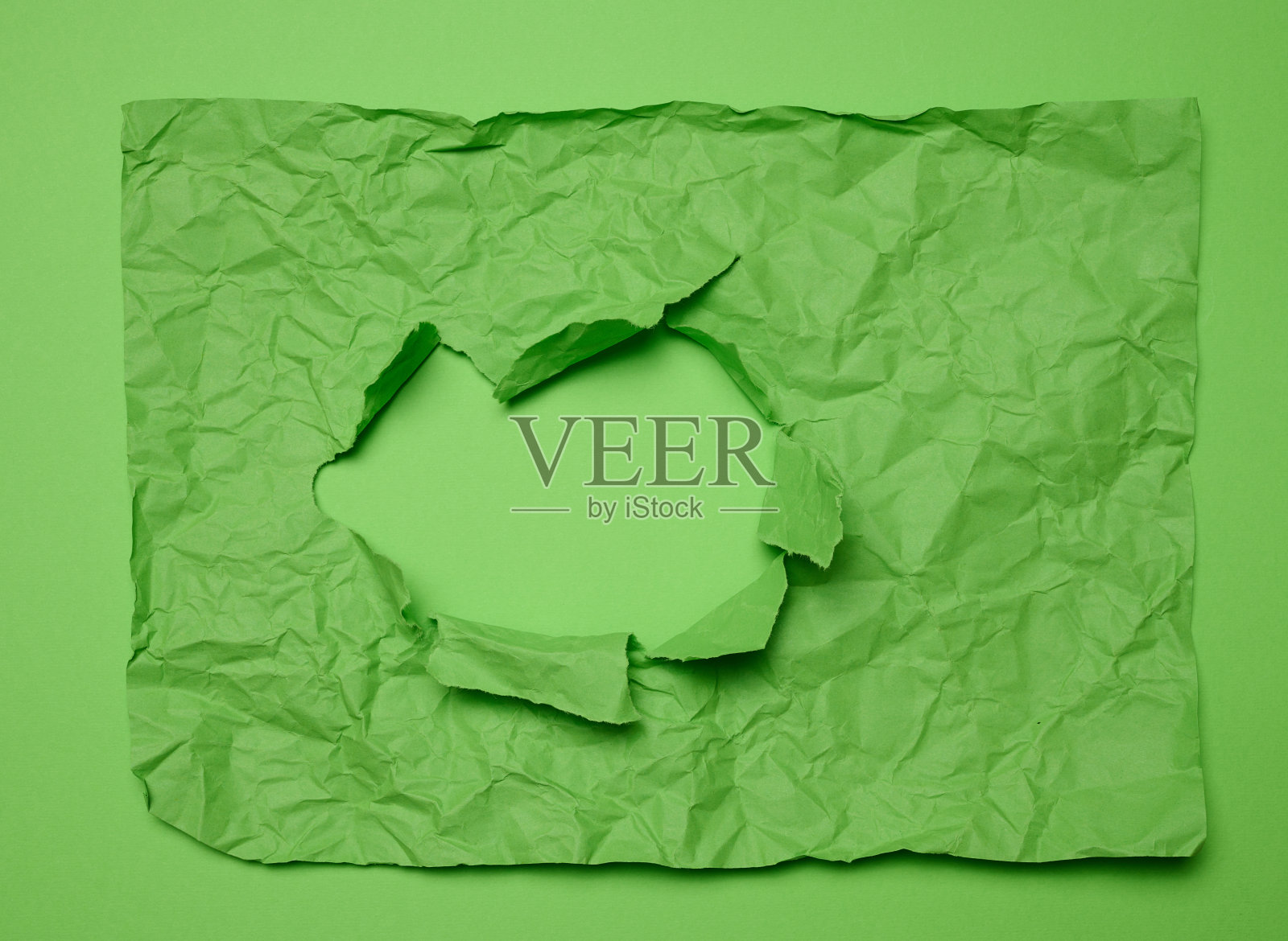 皱褶的绿色纸张纹理与撕裂孔和绿色背景，模板为设计师照片摄影图片