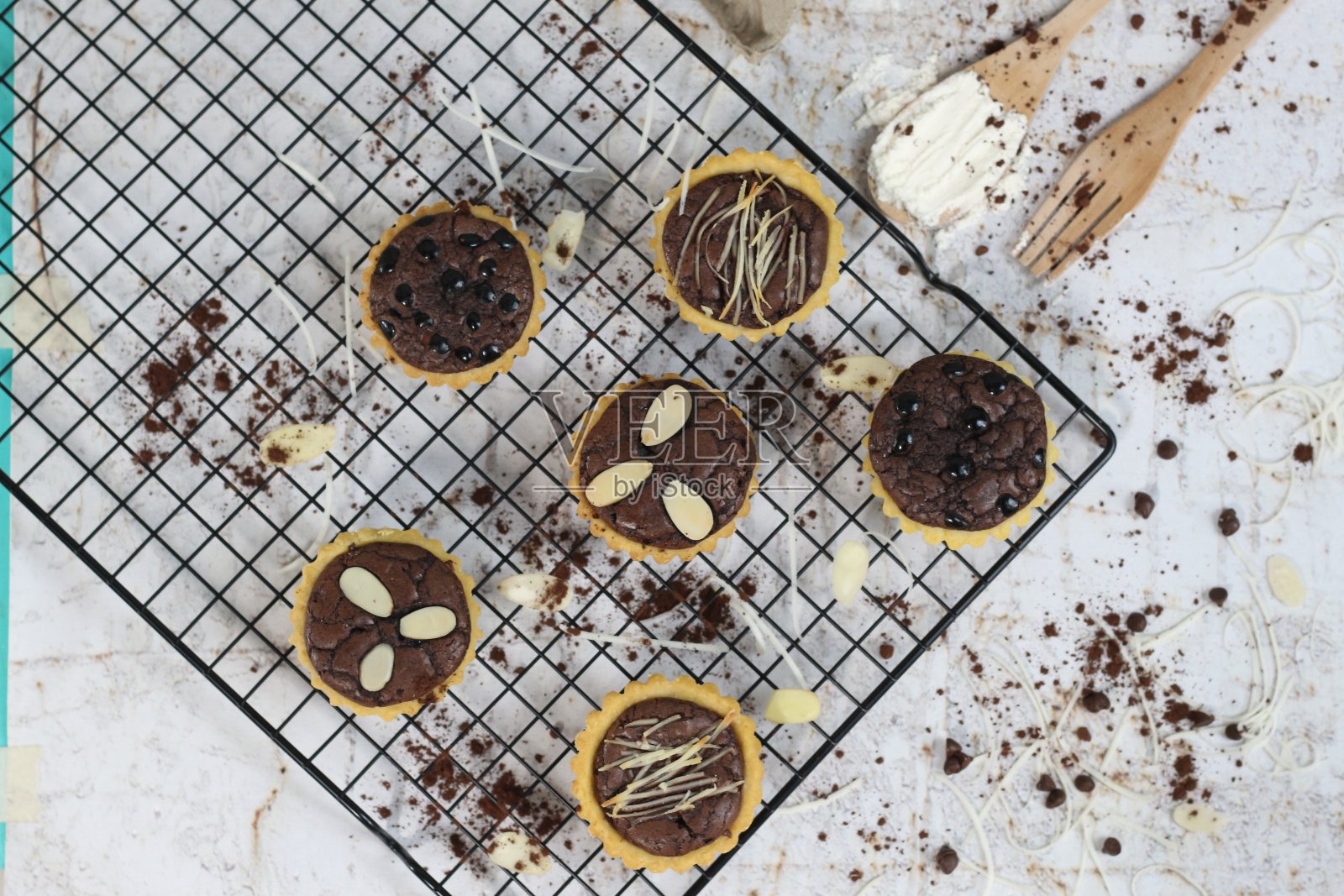 小块巧克力派，上面有杏仁，放在蛋糕架上，吃起来香甜可口。食物概念图。照片摄影图片