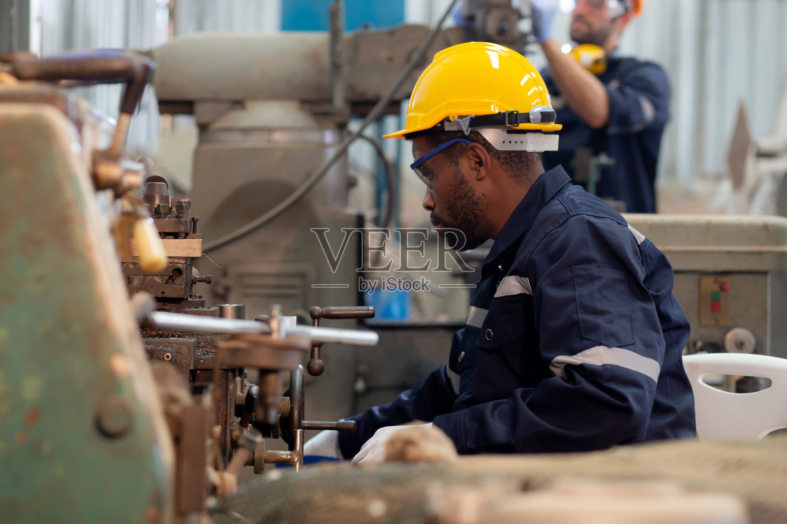 年轻的黑人工程师在工厂操作车床准备生产，工作场所的技术人员或劳动维护机械，金属工人工作，工业概念。照片摄影图片