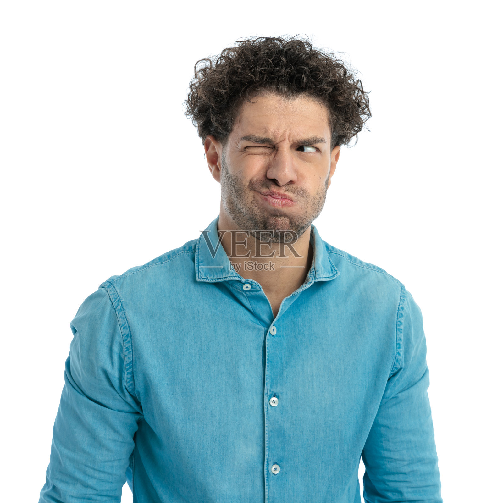 卷发年轻男子做着滑稽的表情看向一侧照片摄影图片