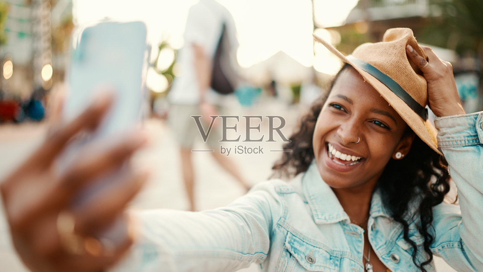 特写肖像的年轻女子长卷发使用手机在城市的城市背景。一个女孩用智能手机发送语音信息的特写镜头照片摄影图片