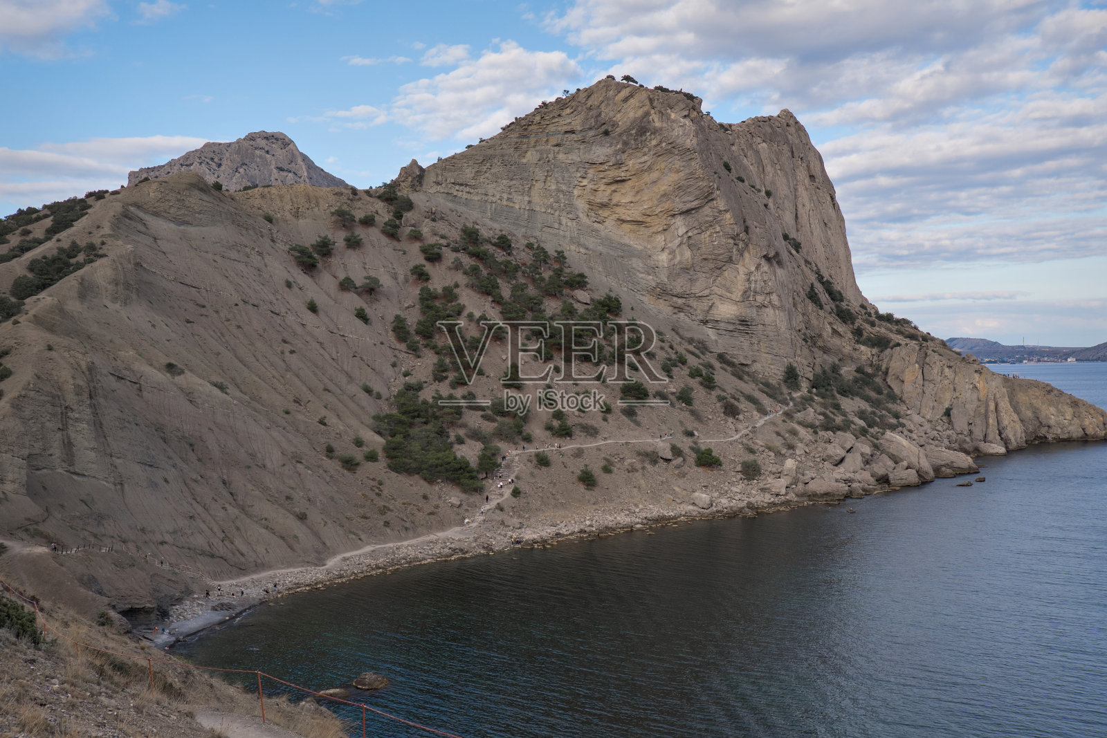 山上的石头路，背景是平静的大海。日落时的岩石和树木，蓝天。晚上放松，放松，冥想。壁纸和屏保照片摄影图片