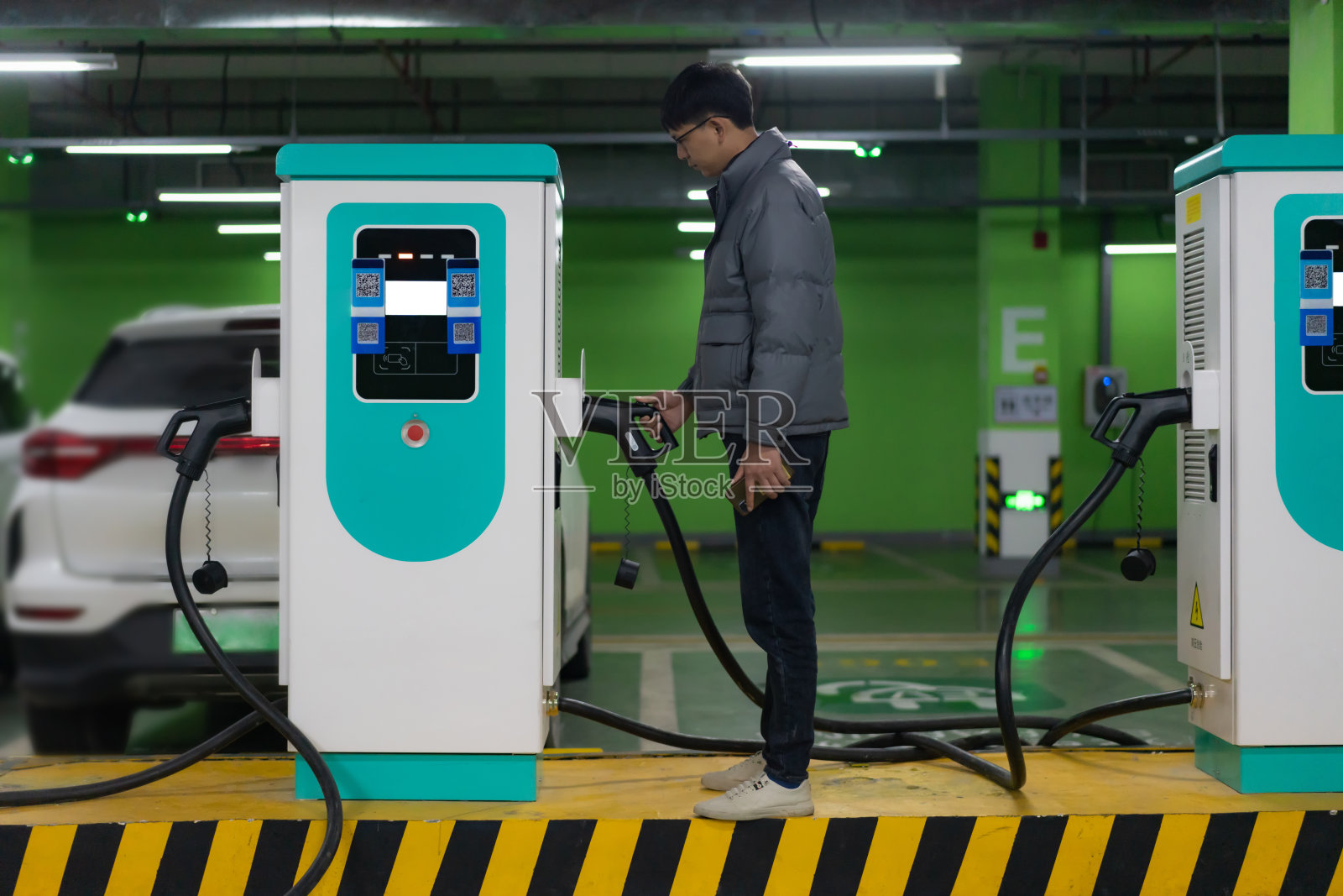 亚洲男子正准备给电动汽车充电照片摄影图片
