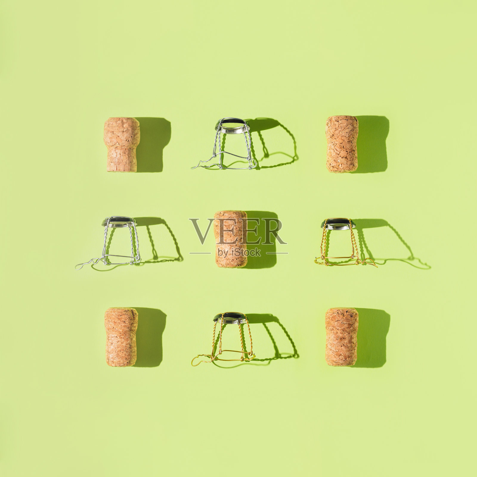 由香槟软木塞在绿色阳光下的背景与阴影的创意组成。起泡酒的瓶盖和金属丝步枪。夏日派对饮品概念。前视图。平躺照片摄影图片