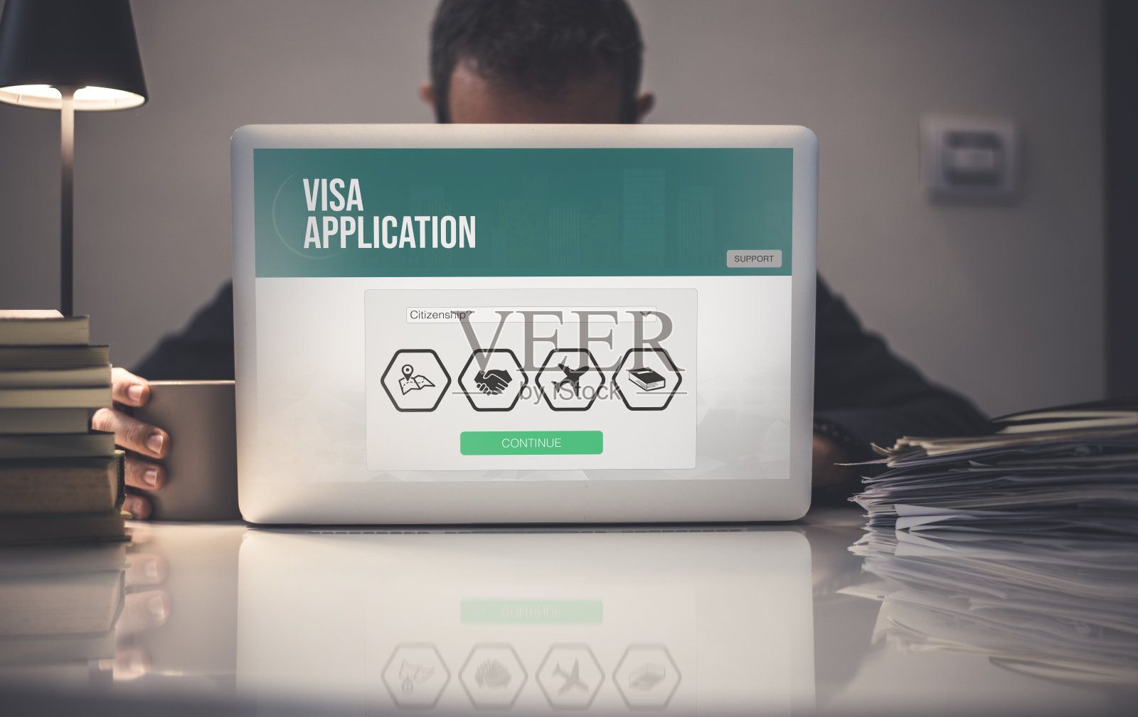 在笔记本电脑上手工填写签证申请表。工作招聘、学习、旅游、移民概念。照片摄影图片