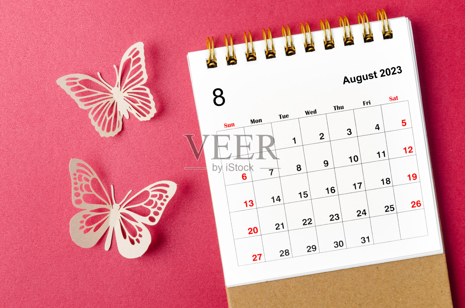 2023年8月日历桌，供组织者规划和提醒，红色背景上有蝴蝶纸。照片摄影图片