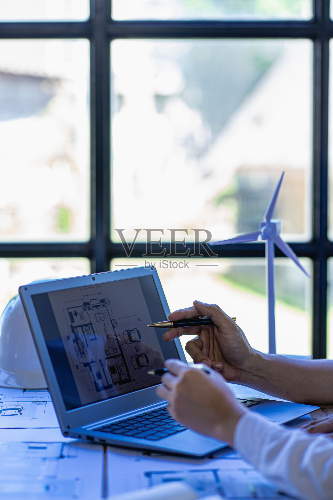 男工程师会议指向蓝图与房屋计划和风力涡轮机旁边的房屋建筑概念与风力涡轮机可再生能源安装照片摄影图片