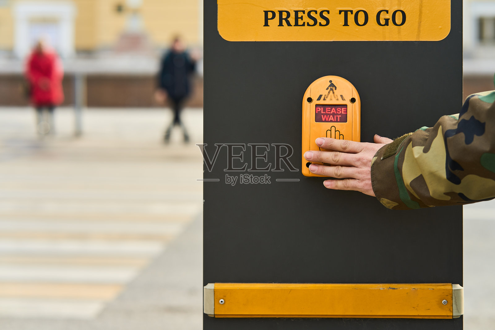 一名男子的手按下交通灯传感器，使绿灯亮起照片摄影图片